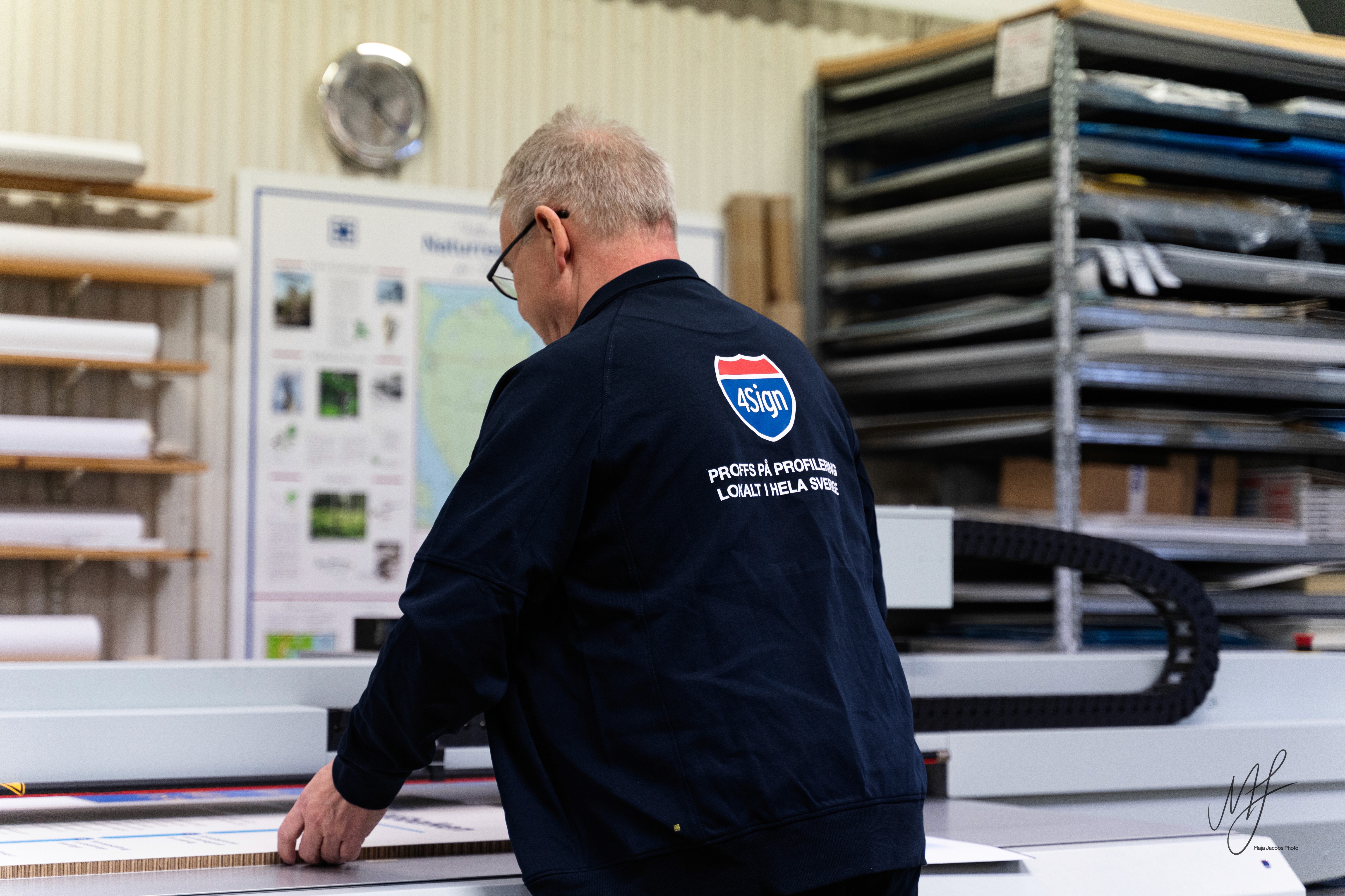 Kund granskar arbetskläder och varselkläder i 4Signs butik, brett utbud av profilprodukter.