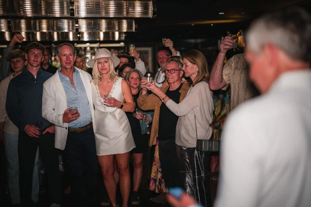 The bride, groom and surrounding guests hold up their glasses during a wedding toast.