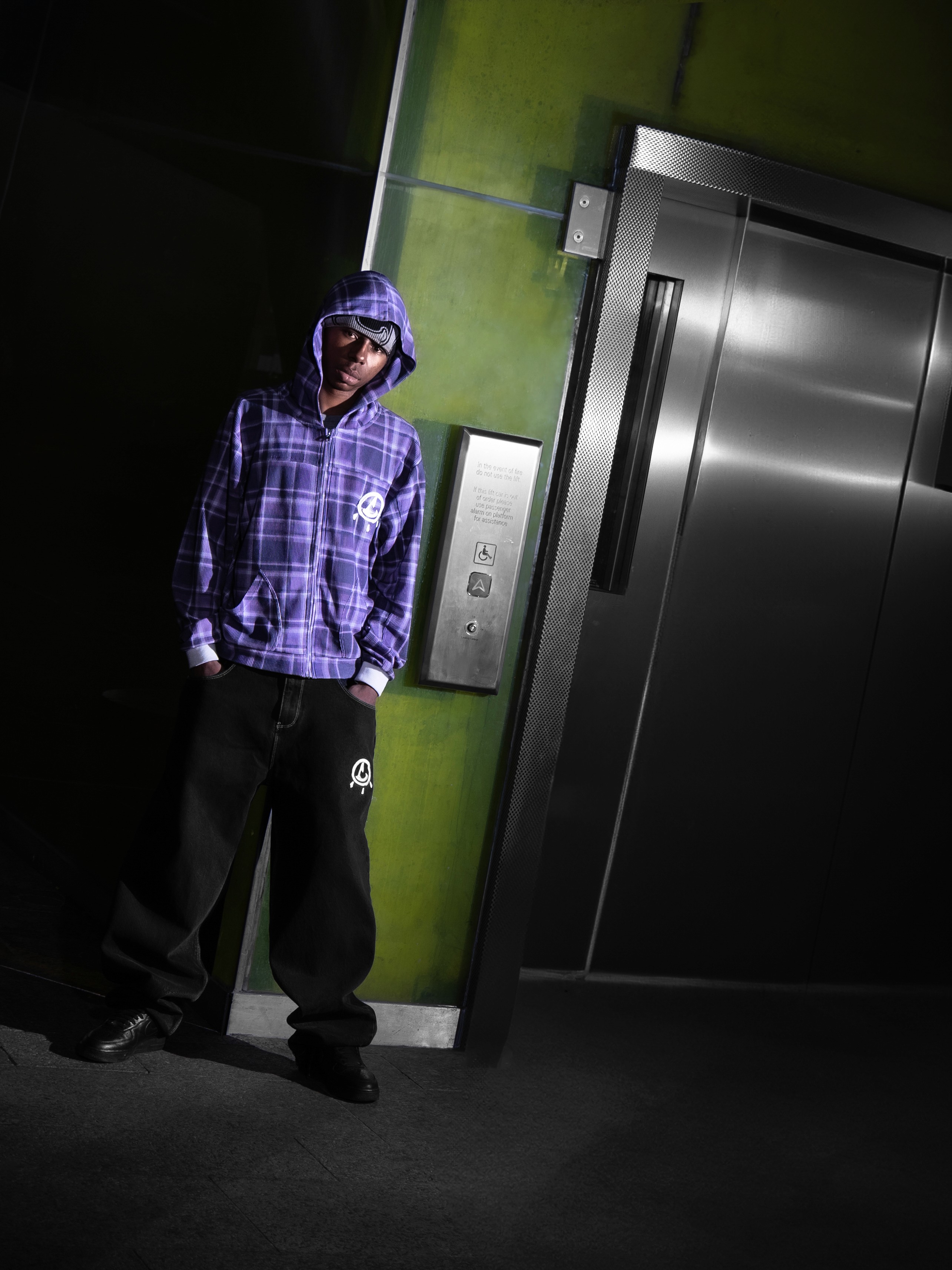 Man in a sporty jacket and light shorts walking across a football field, confidently pulling on his collar.