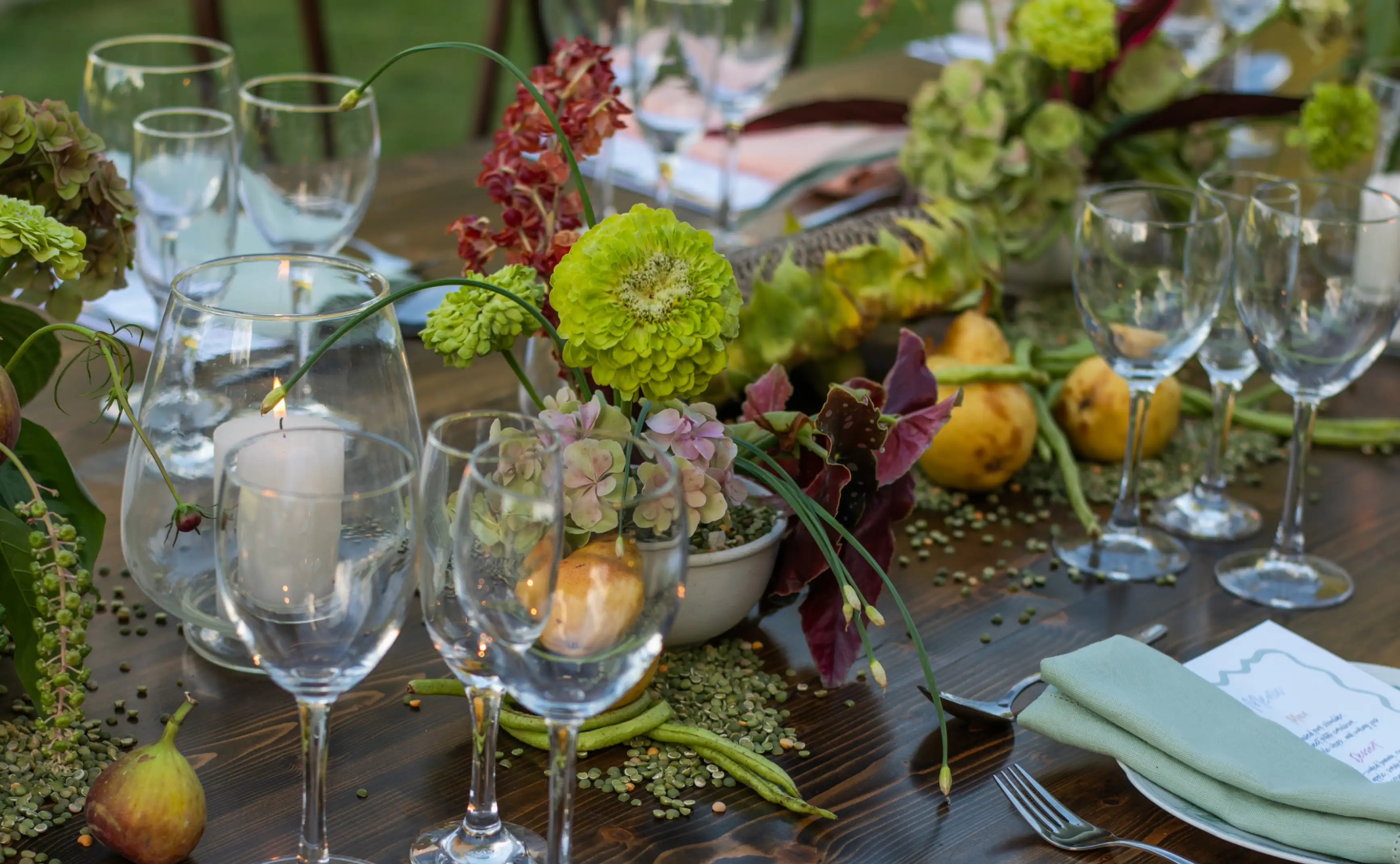 Detalle de mesa con flores verdes y frutas naturales para ambientación orgánica y sofisticada de banquete exterior.