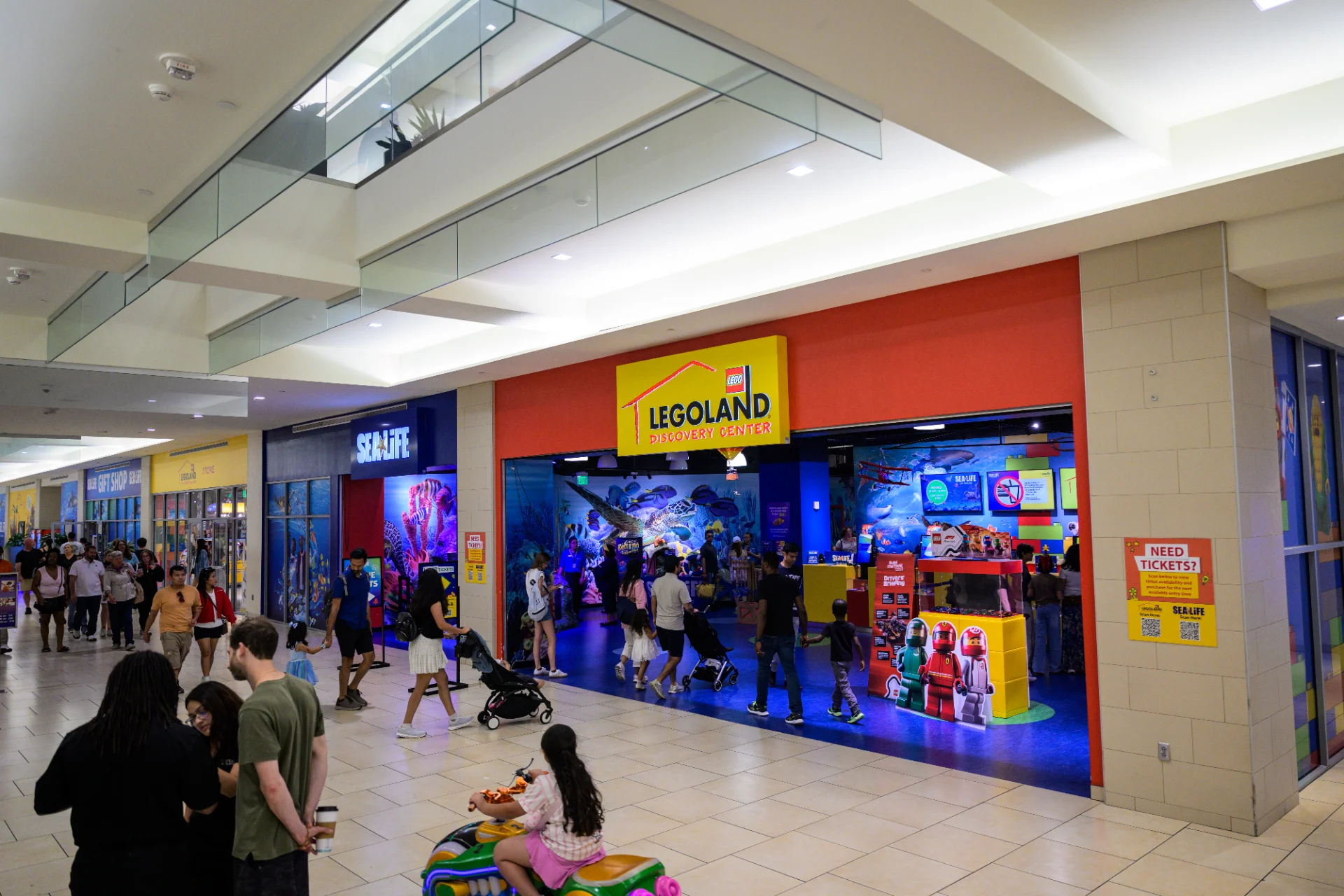Legoland Discovery Center and Sea Life entrances inside the Shops at Rivercenter, with families walking through the mall corridor