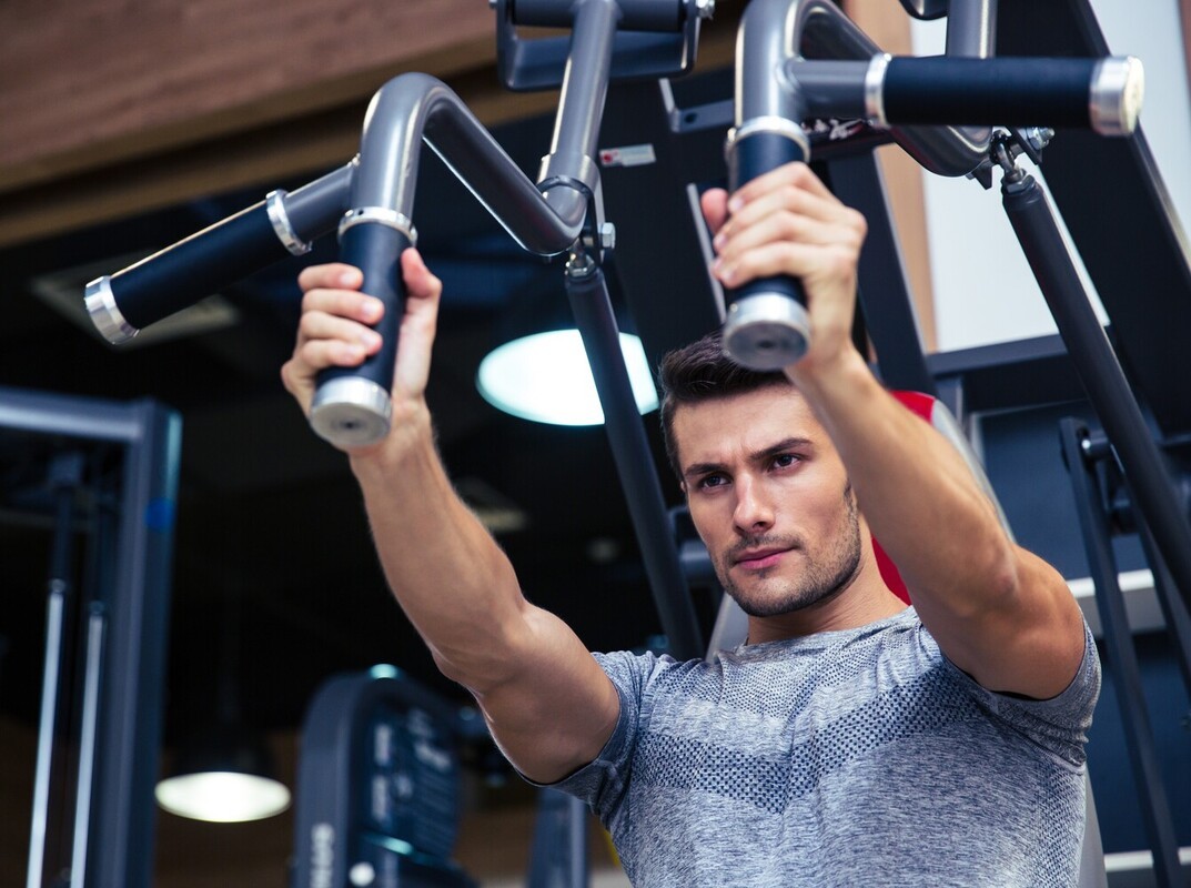 man using the best exercise machine for weight loss for upper body strength at the gym