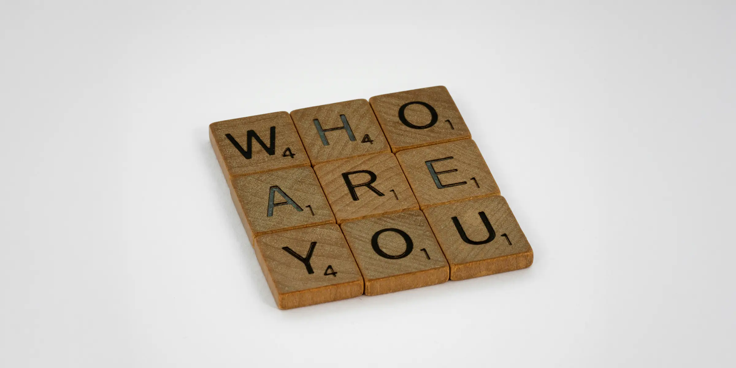 image with a 3x3 grid of wooden scrabble tiles spelling out "who are you"