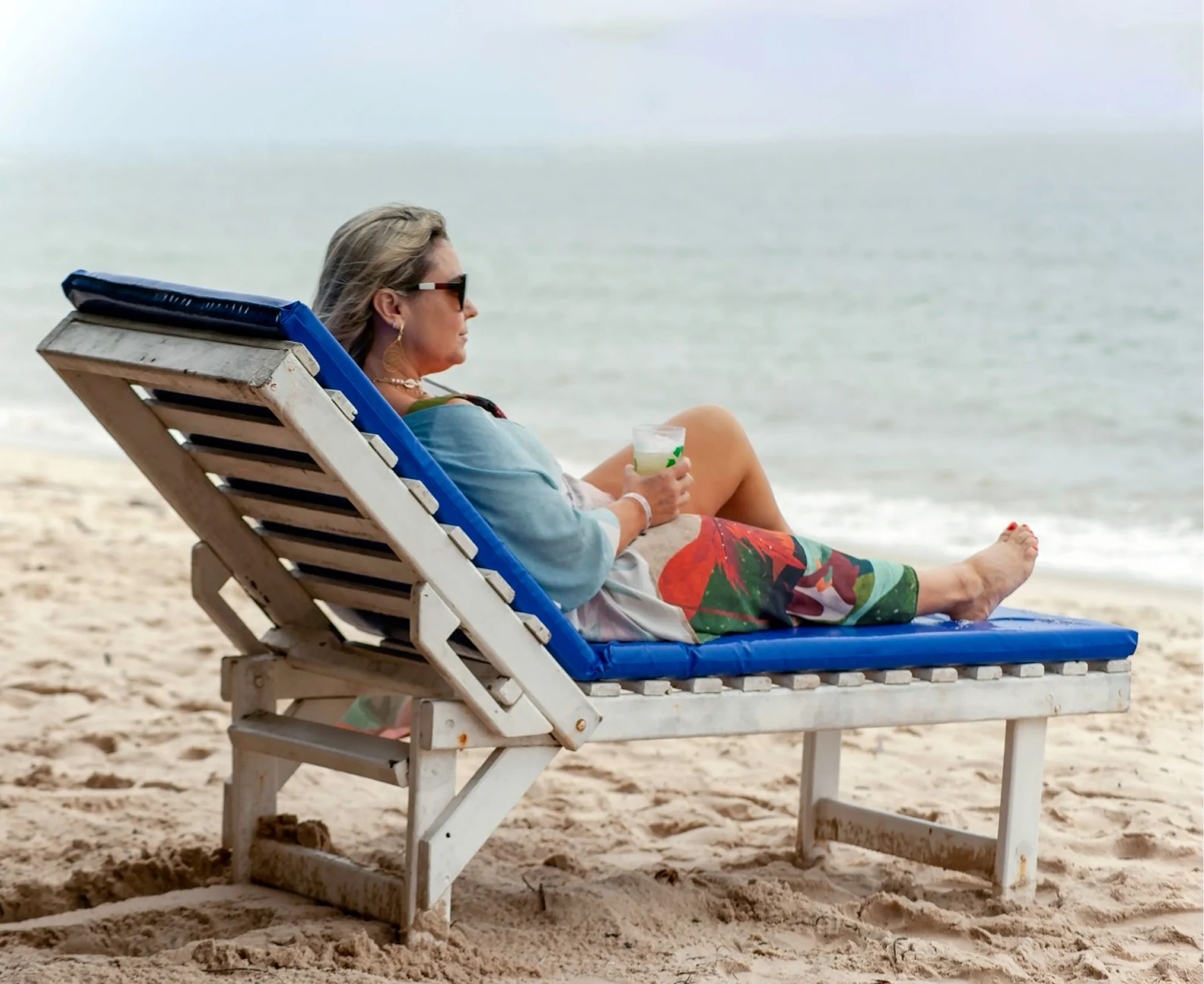 A guest relaxing on a beach lounge chair beside the ocean.