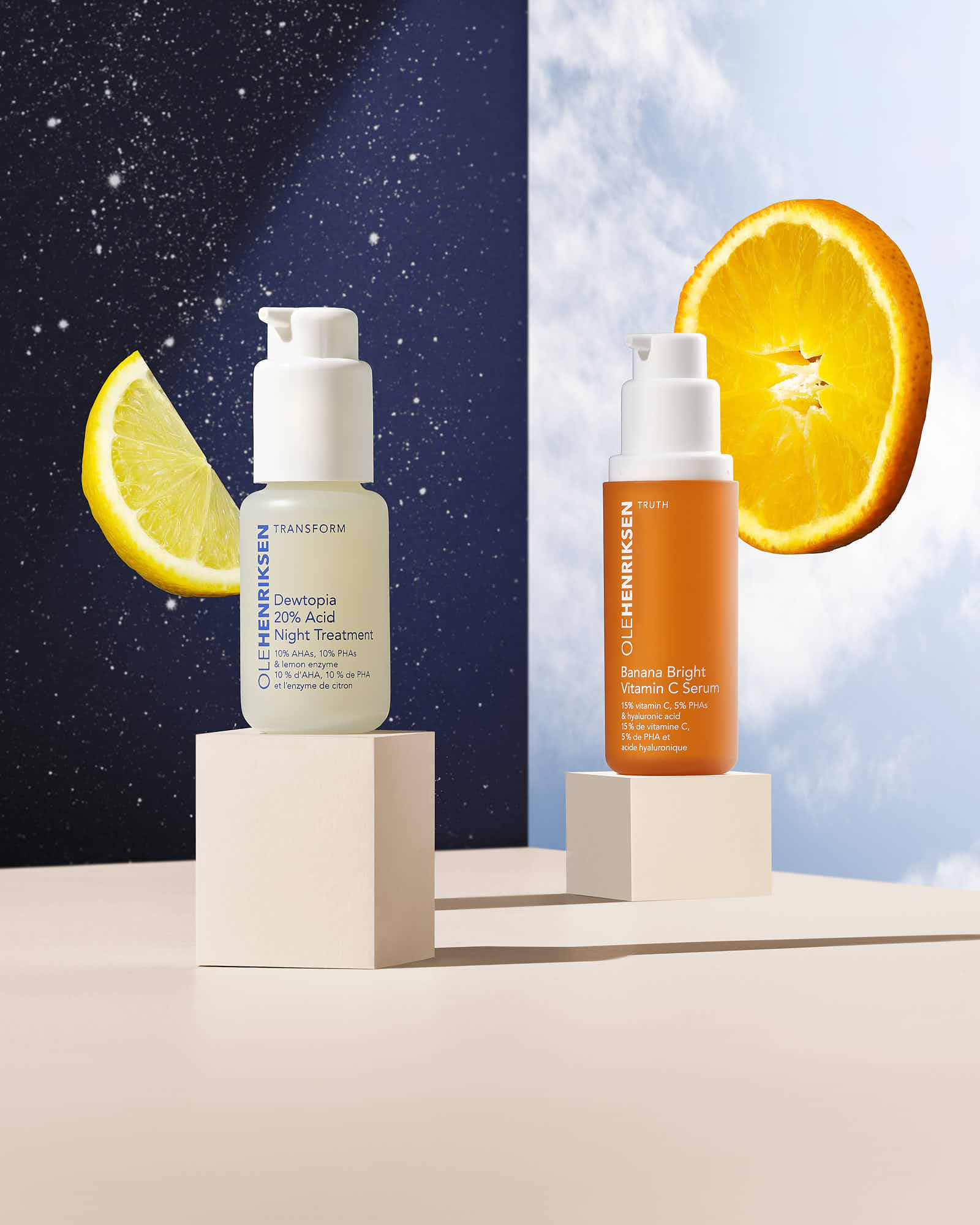 Two skincare bottles sit on a light wooden stand, with a lemon and orange slice in the background.