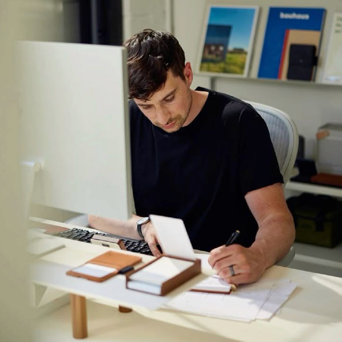 Two colleagues collaborating at a desk, looking at a laptop screen and discussing something with interest.