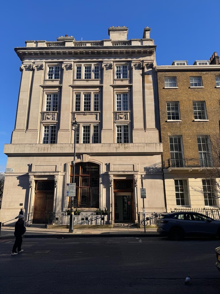Exterior building entrance of the dermatology clinic located on Harley Street, London, featuring a classic white stone facade.