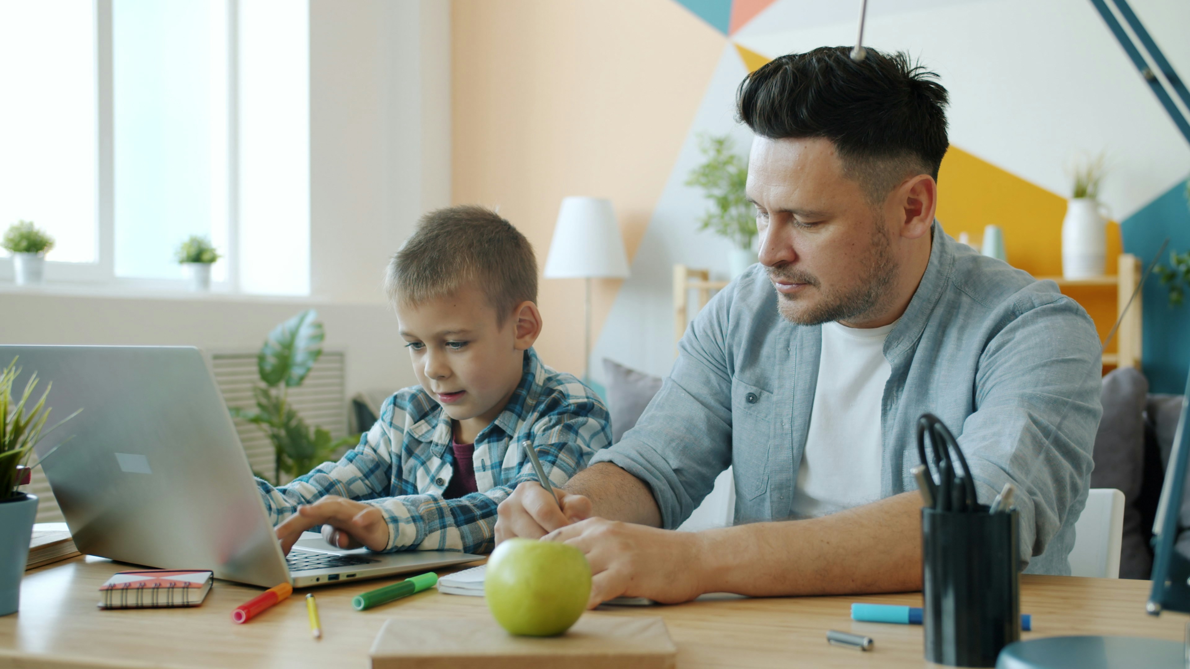 Father and son working together on a laptop.