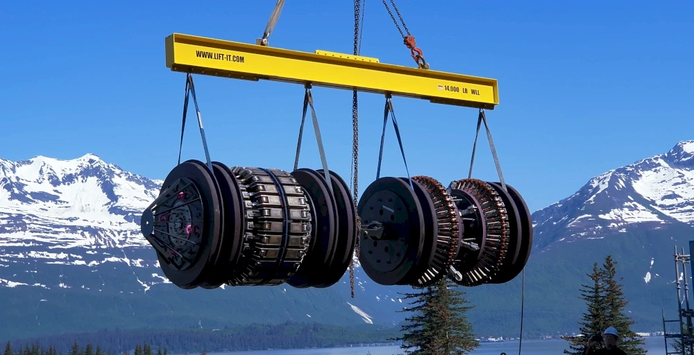 Heavy machinery parts being lifted by a crane against a mountain backdrop. Engineering and construction.