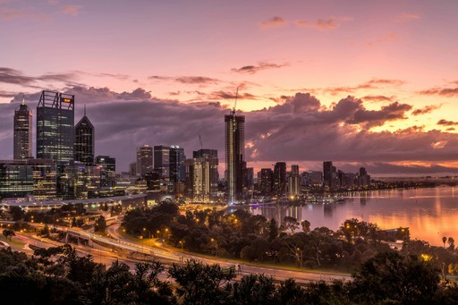 a city skyline with a river and a sunset