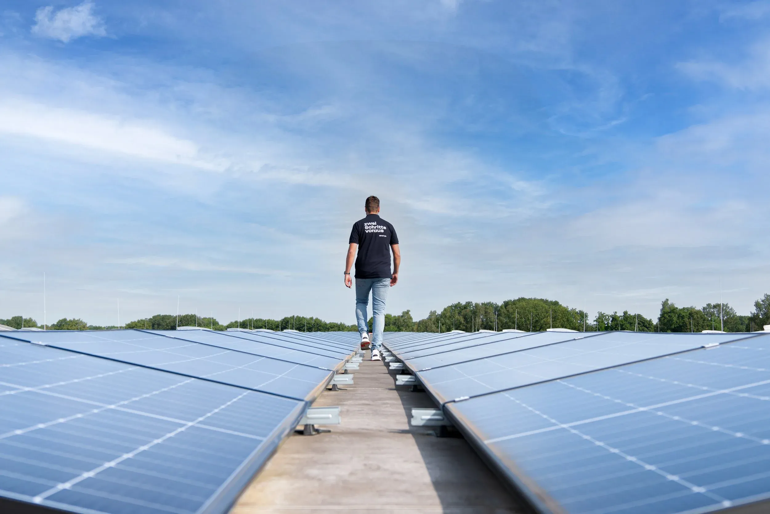 Mann geht auf Dach zwischen Solarpanels