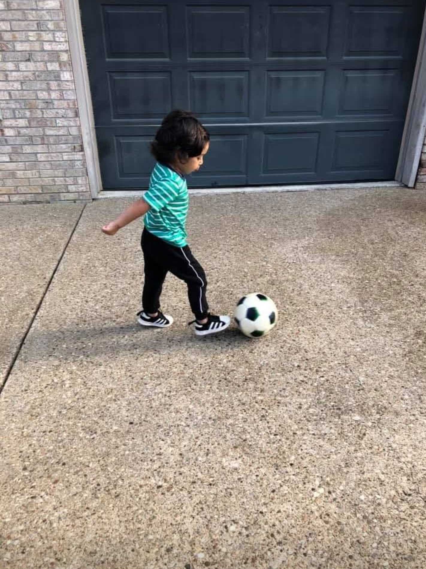 small kid playing kicking a soccer ball