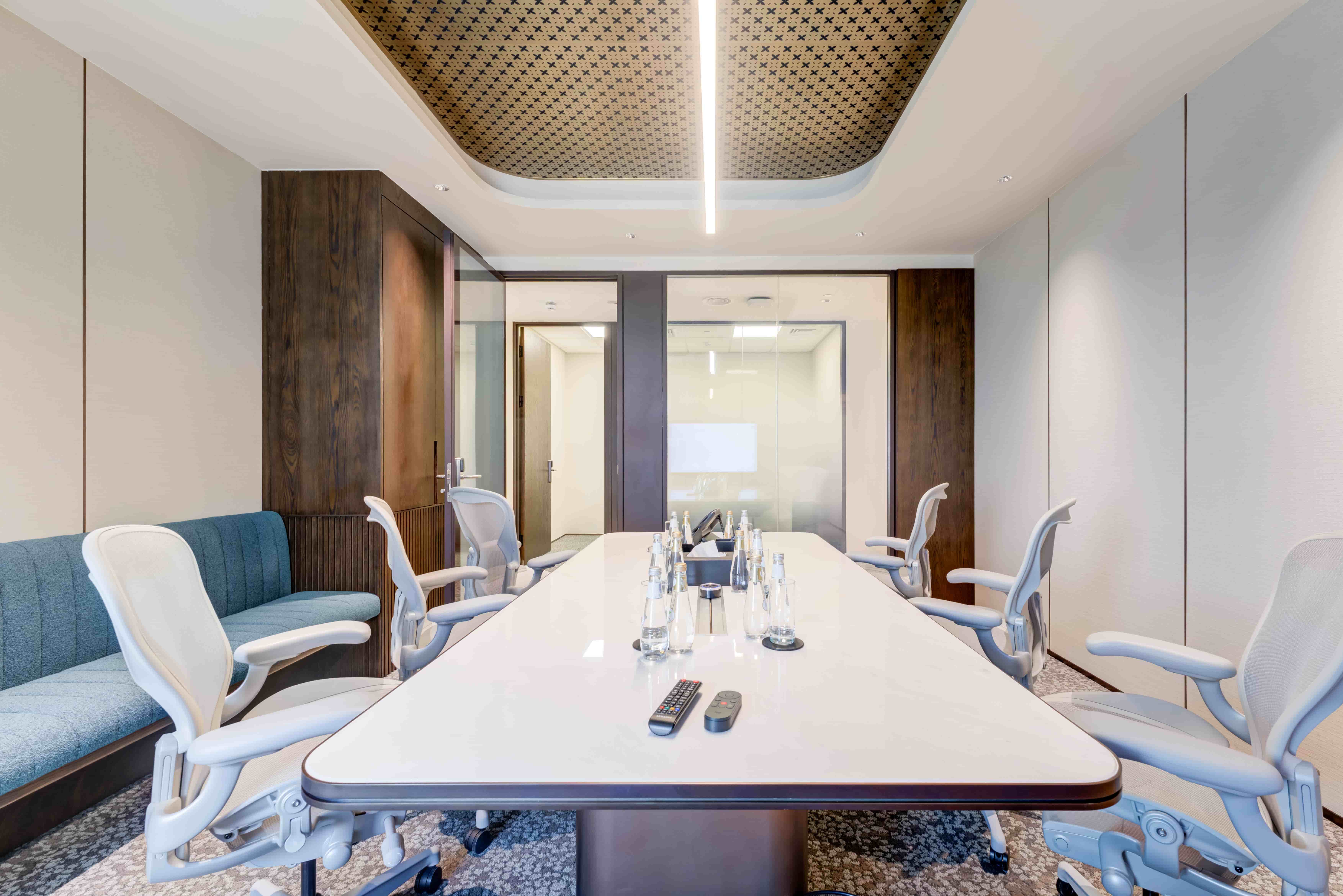 Image alt text: Private meeting room in Riyadh with a long conference table, office chairs, wall seating, and glass doors