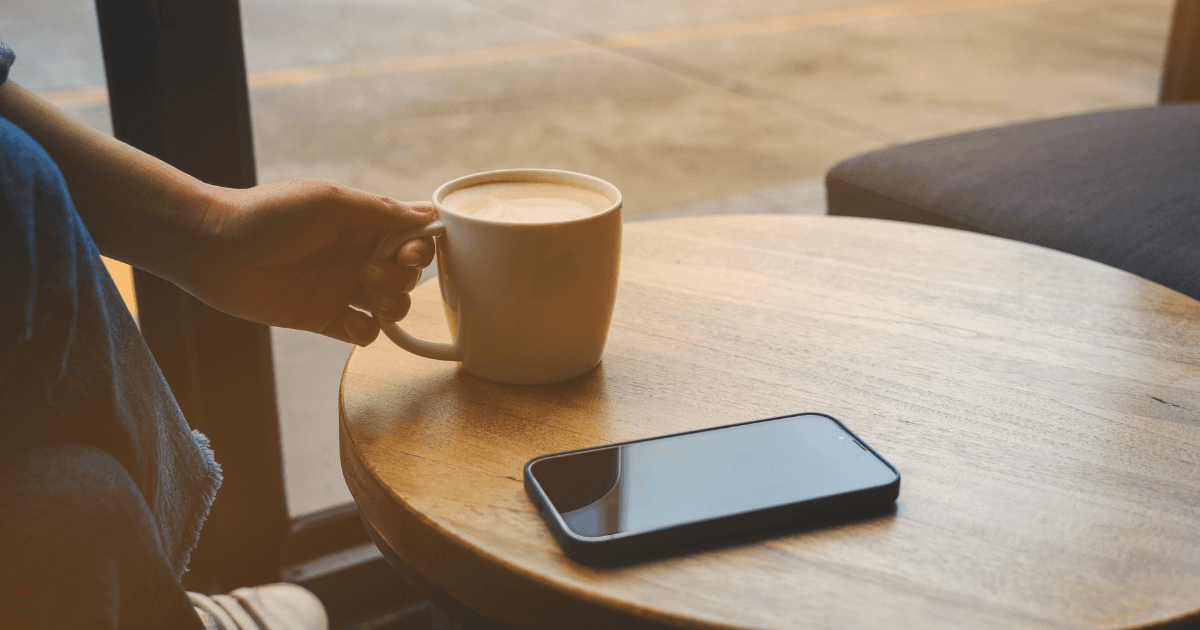 close van handen met een telefoon en koffie in de handen
