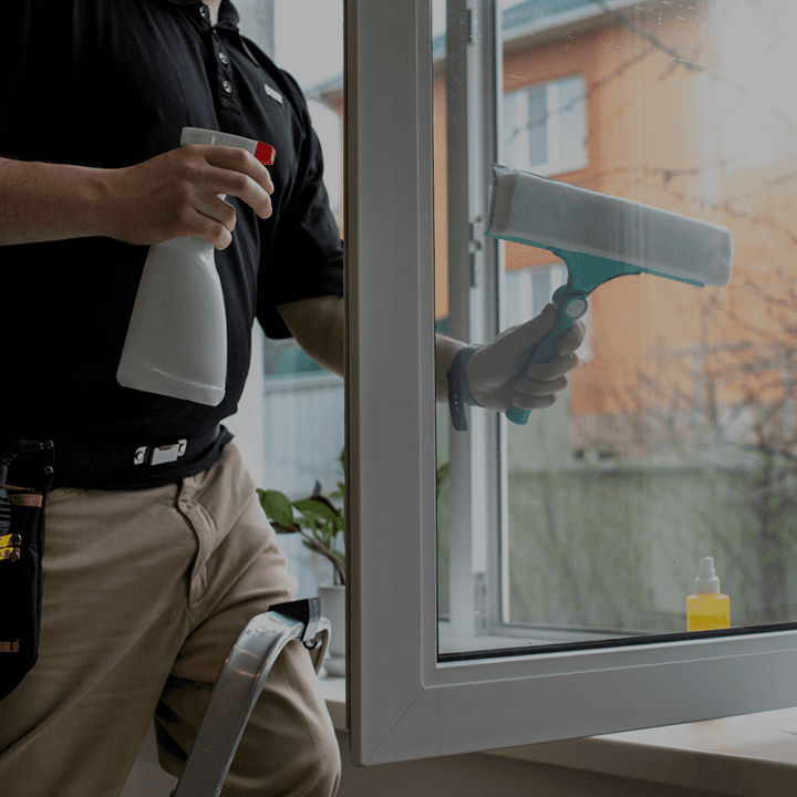 Un homme nettoie une vitre avec une raclette dans le 90 à Bavilliers
