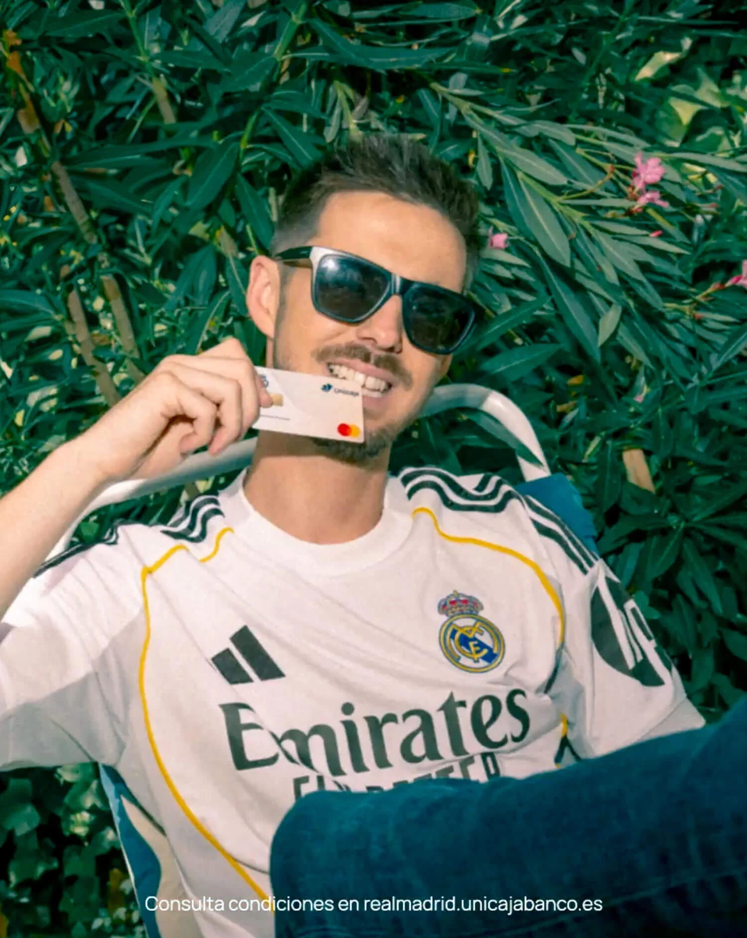 Primer plano de un seguidor luciendo la equipación oficial del Real Madrid y mostrando su Tarjeta Madridista Premium de Unicaja