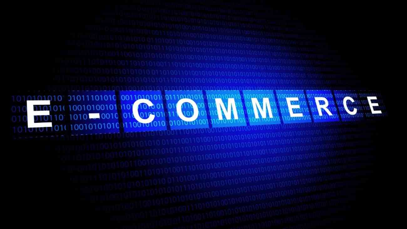 The word e-commerce highlighted in blue in front of a screen with binary numbers