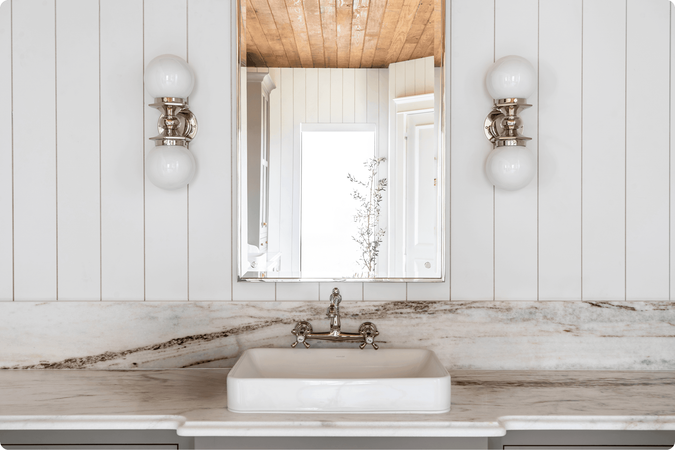 Elegant farmhouse bathroom featuring white marble countertops, vessel sink, chrome sconces, and white shiplap walls