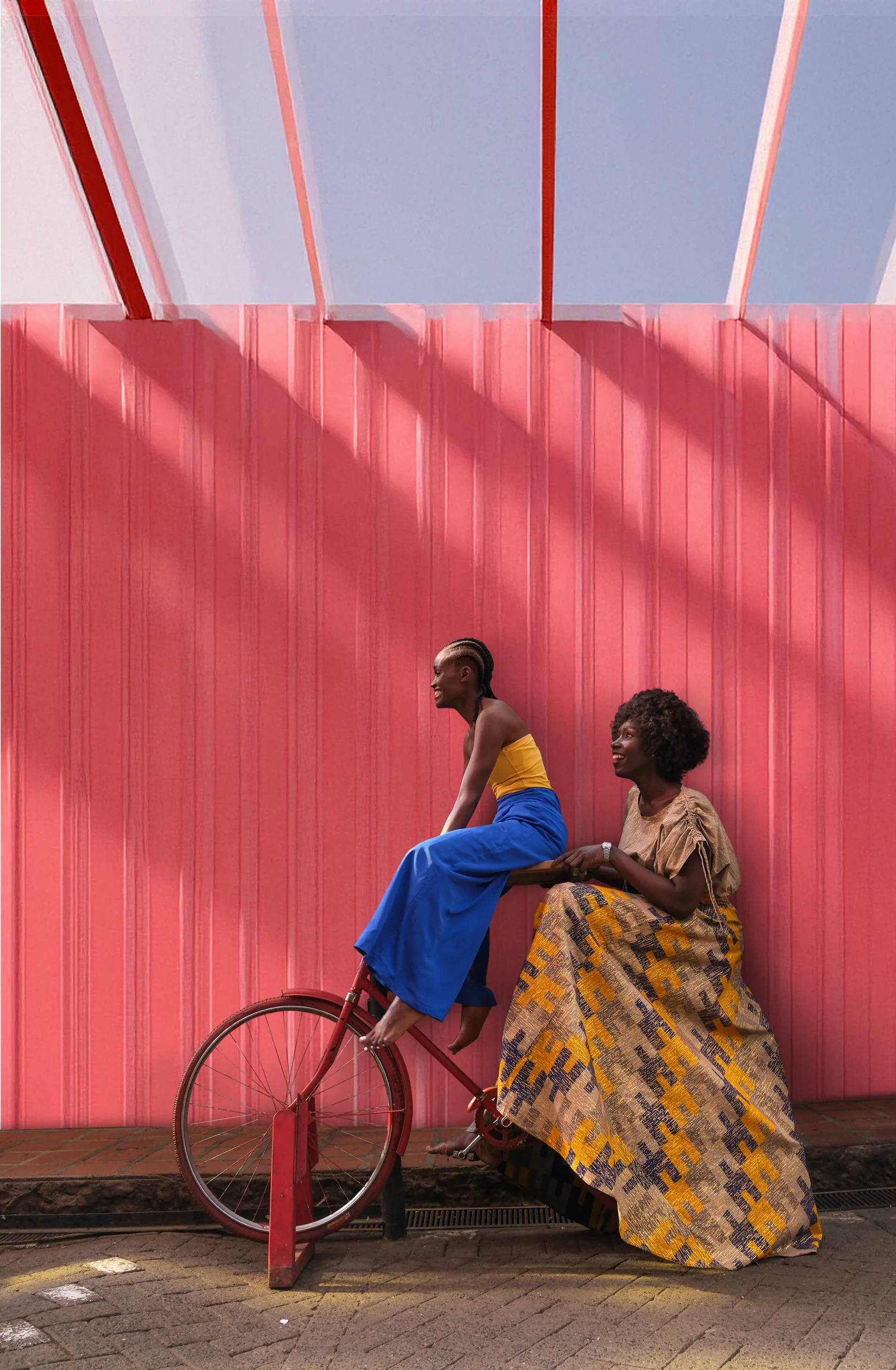 Two people talking near a colorful red building