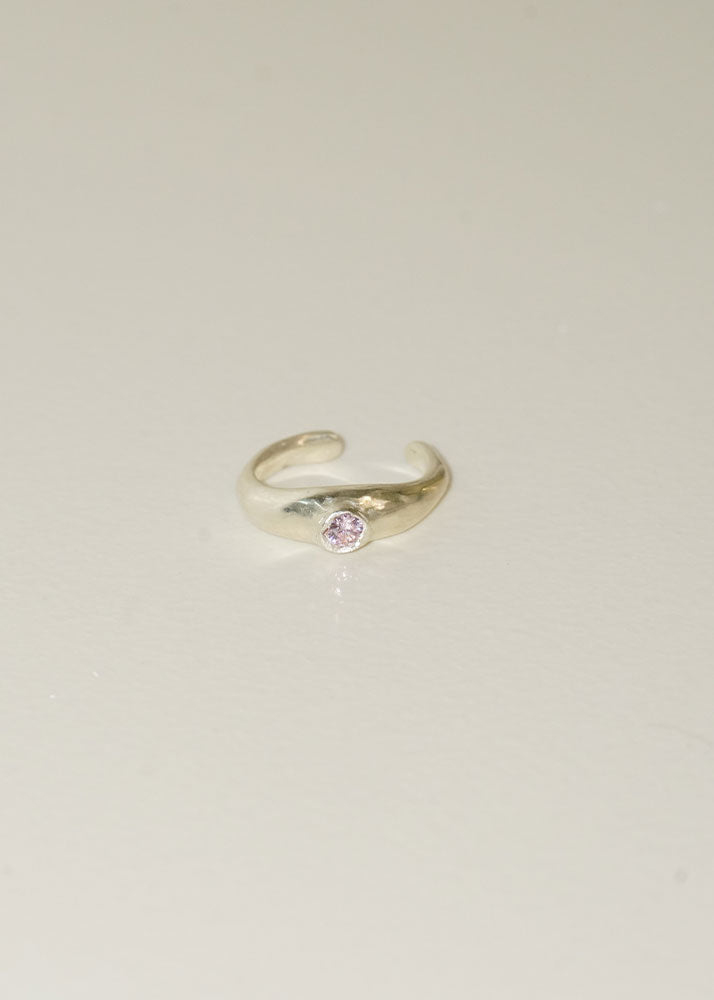 Silver ring with a pink gemstone on a light beige background