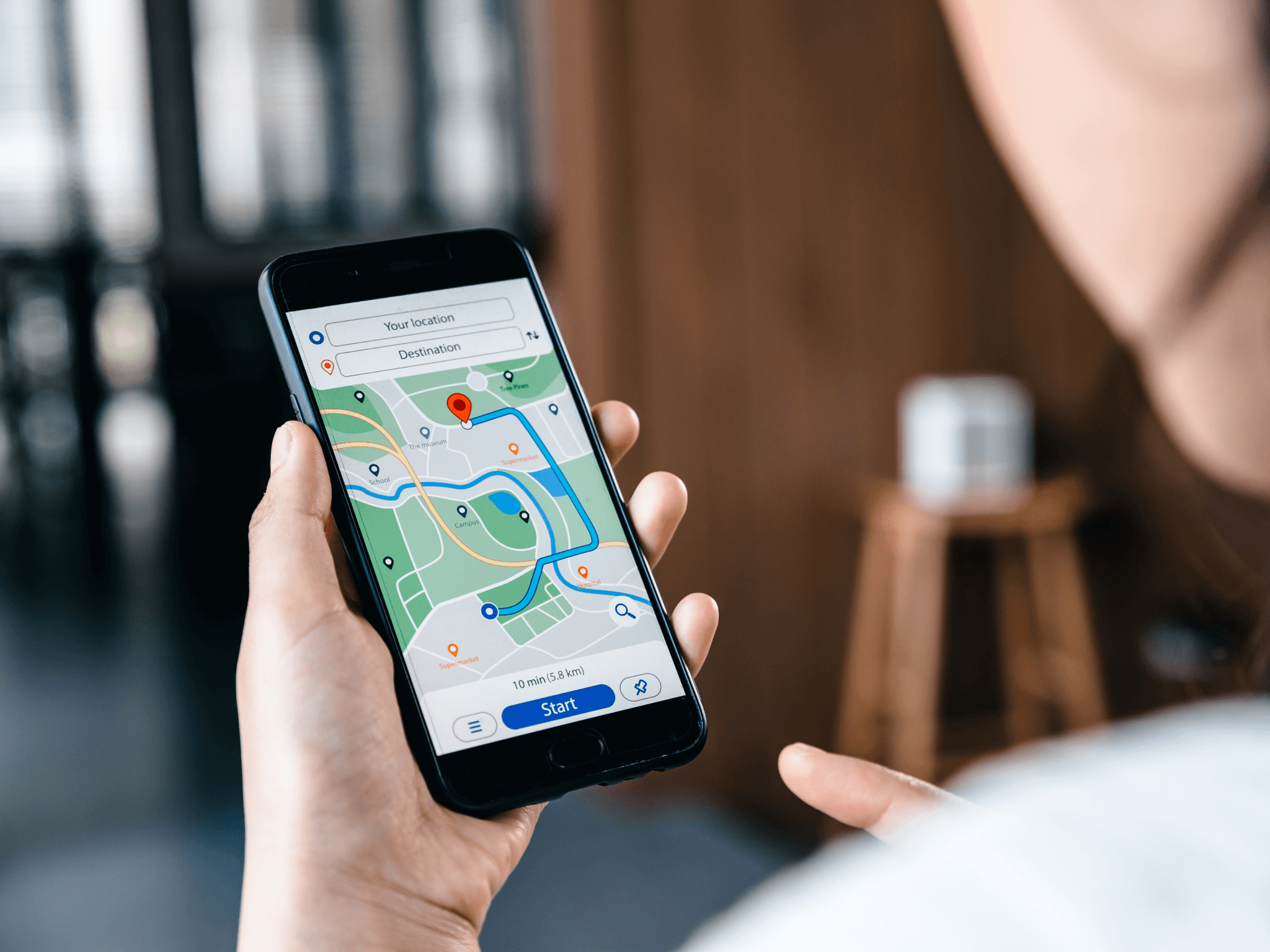 Someone holds up their phone with Google Maps open, showing a route to a chosen destination nearby.