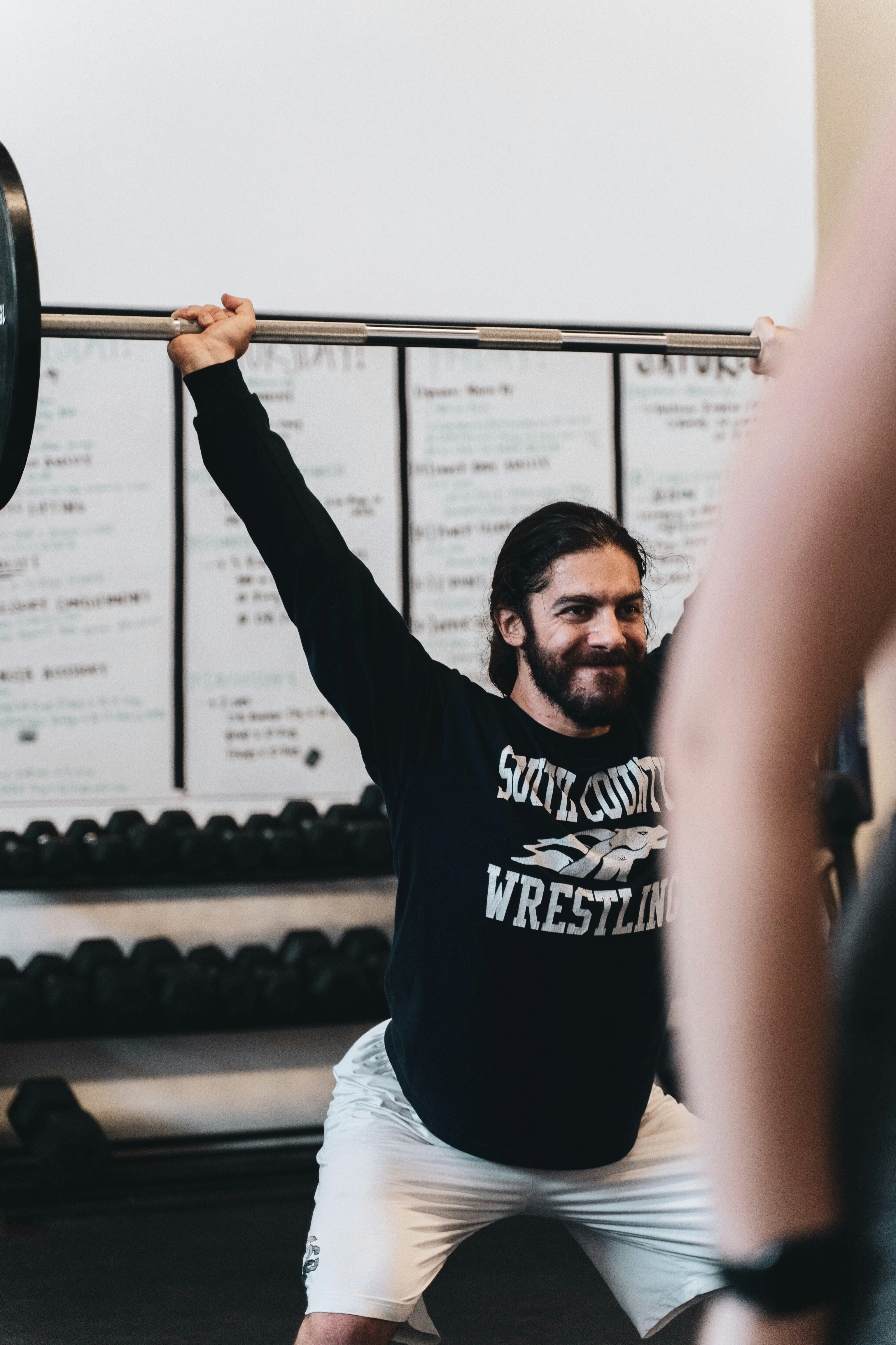 man in black crew neck t-shirt holding black barbell