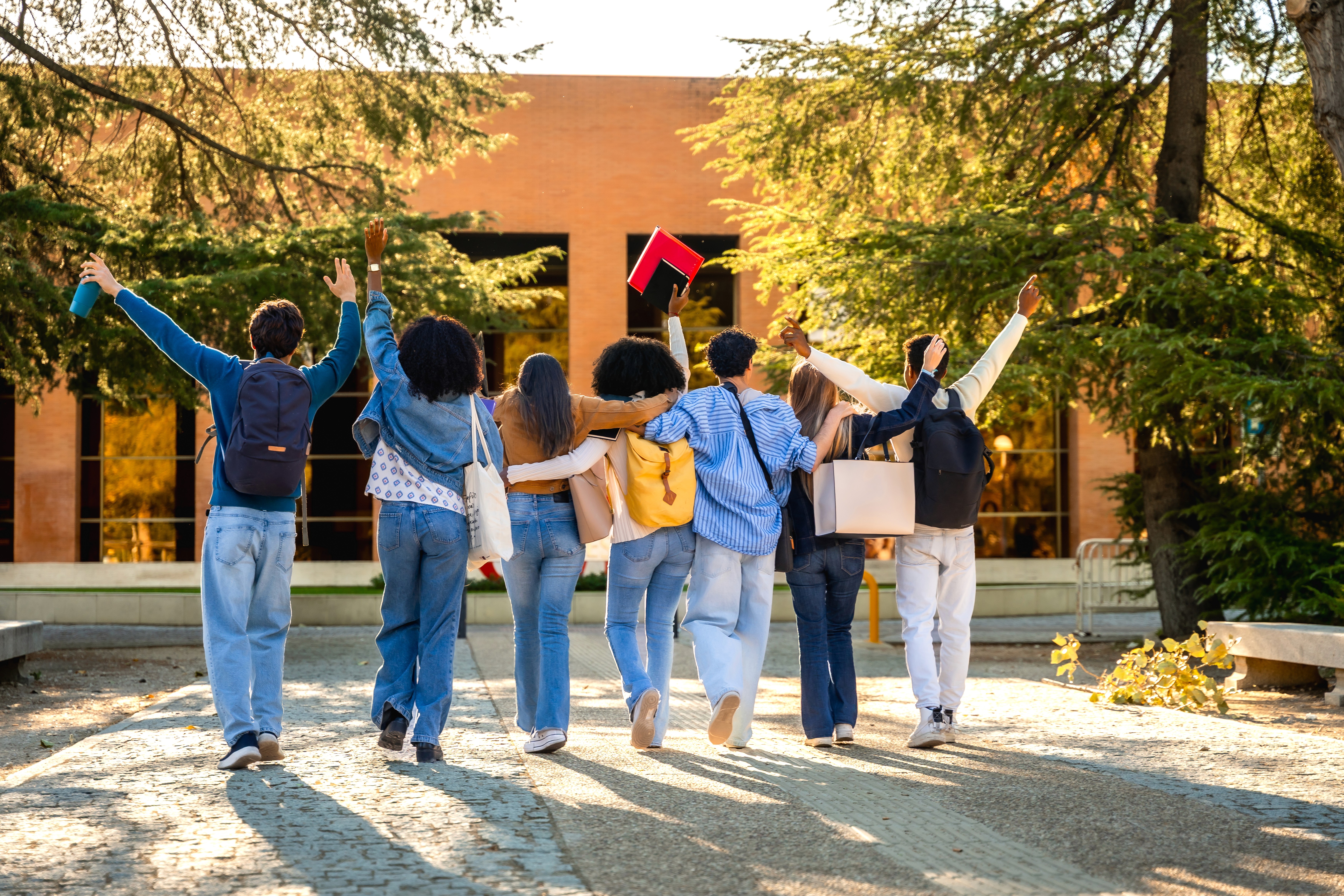 Gruppe von Schüler:innen läuft gemeinsam und fröhlich vor dem Schulgebäude und feiert Lernerfolge und Gemeinschaft