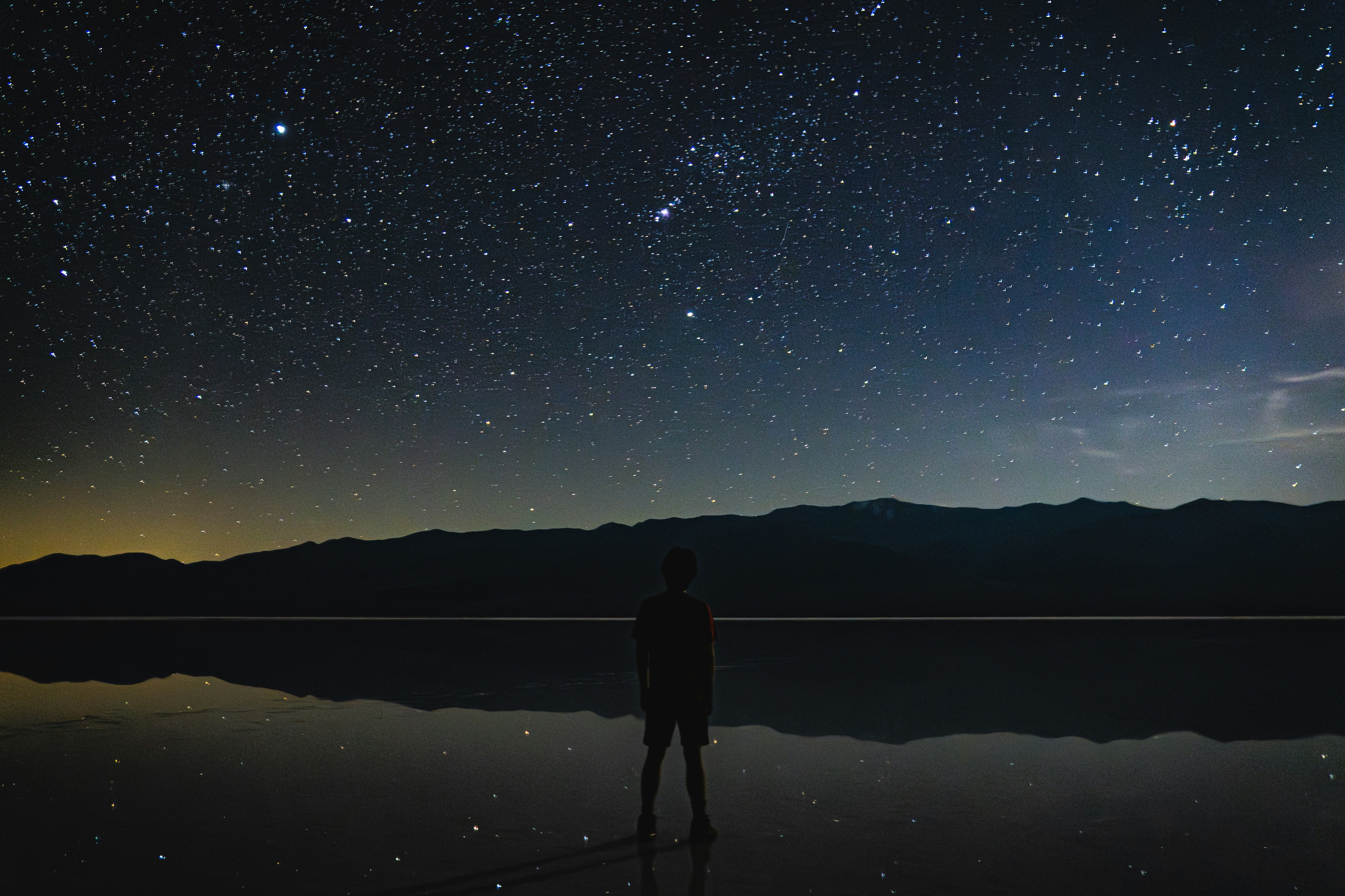 A person stands under a starry night sky.