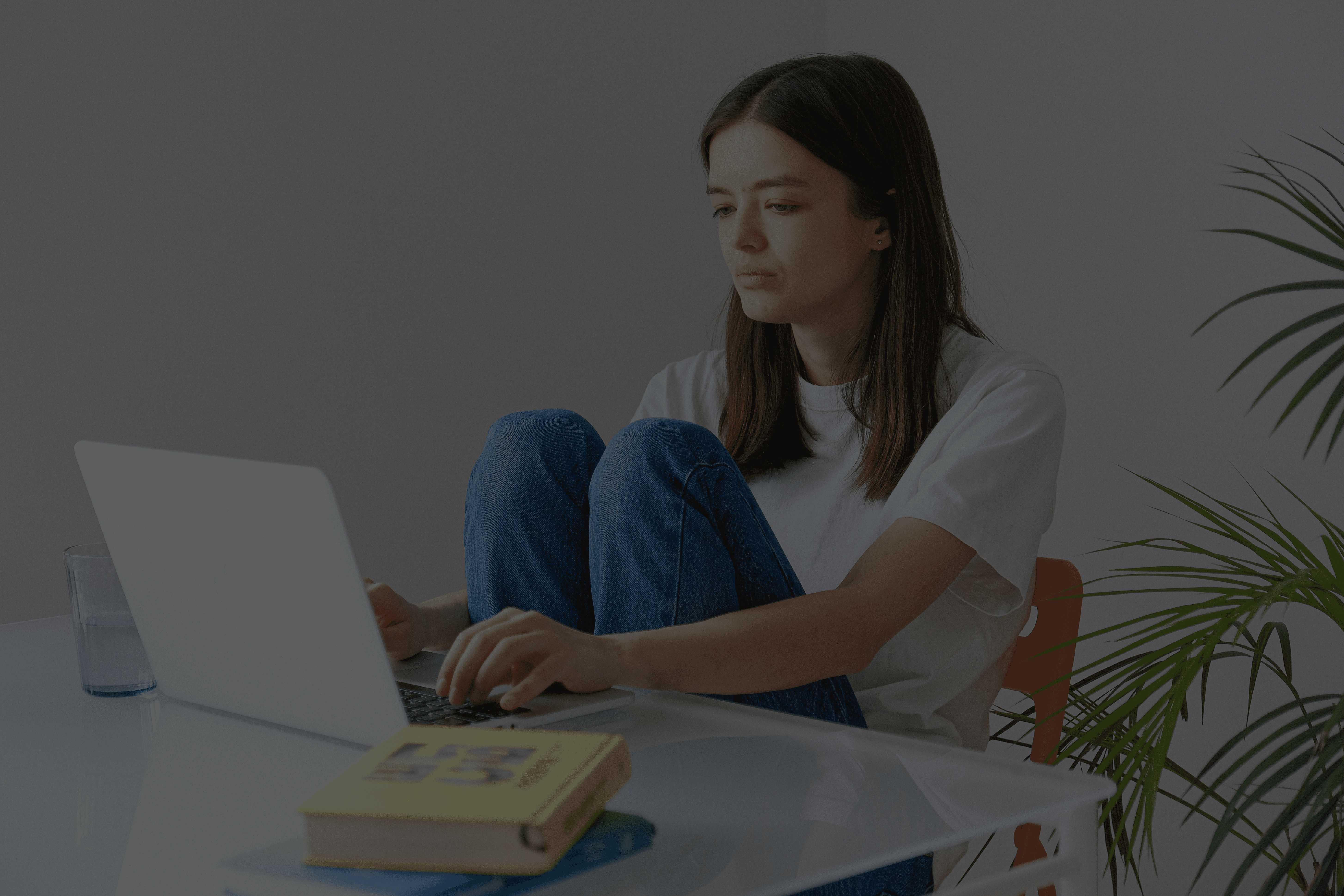 A young woman sitting at a desk with a laptop, representing the cycle of Googling symptoms and seeking reassurance that drives health anxiety.