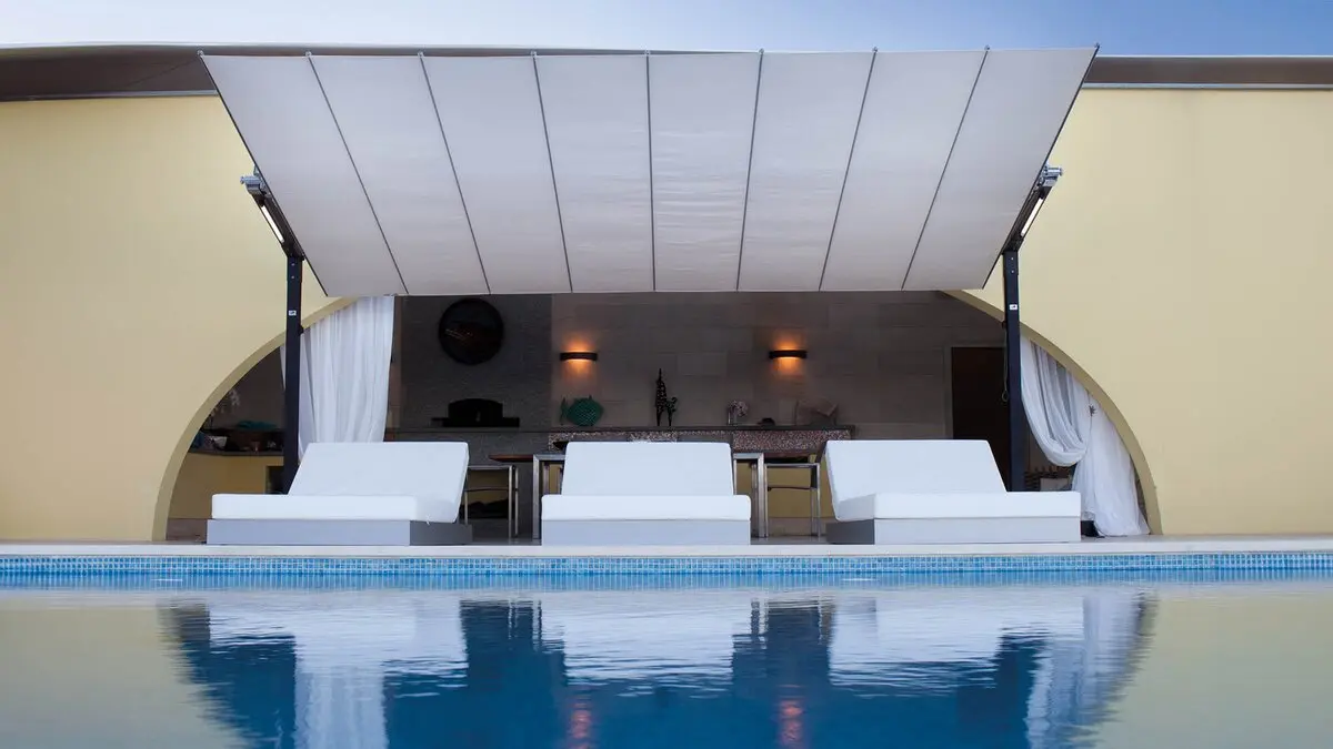Camas al borde de una psicina en alojamiento de lujo con parasol Flexy de Fim