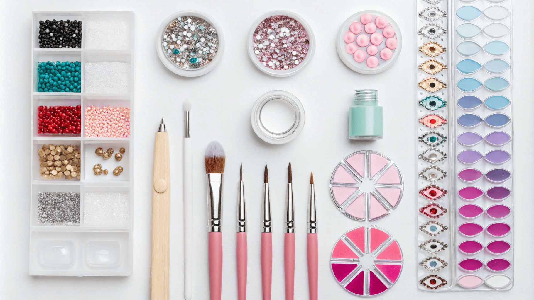 Colorful nail art glitter and tools laid on a white table