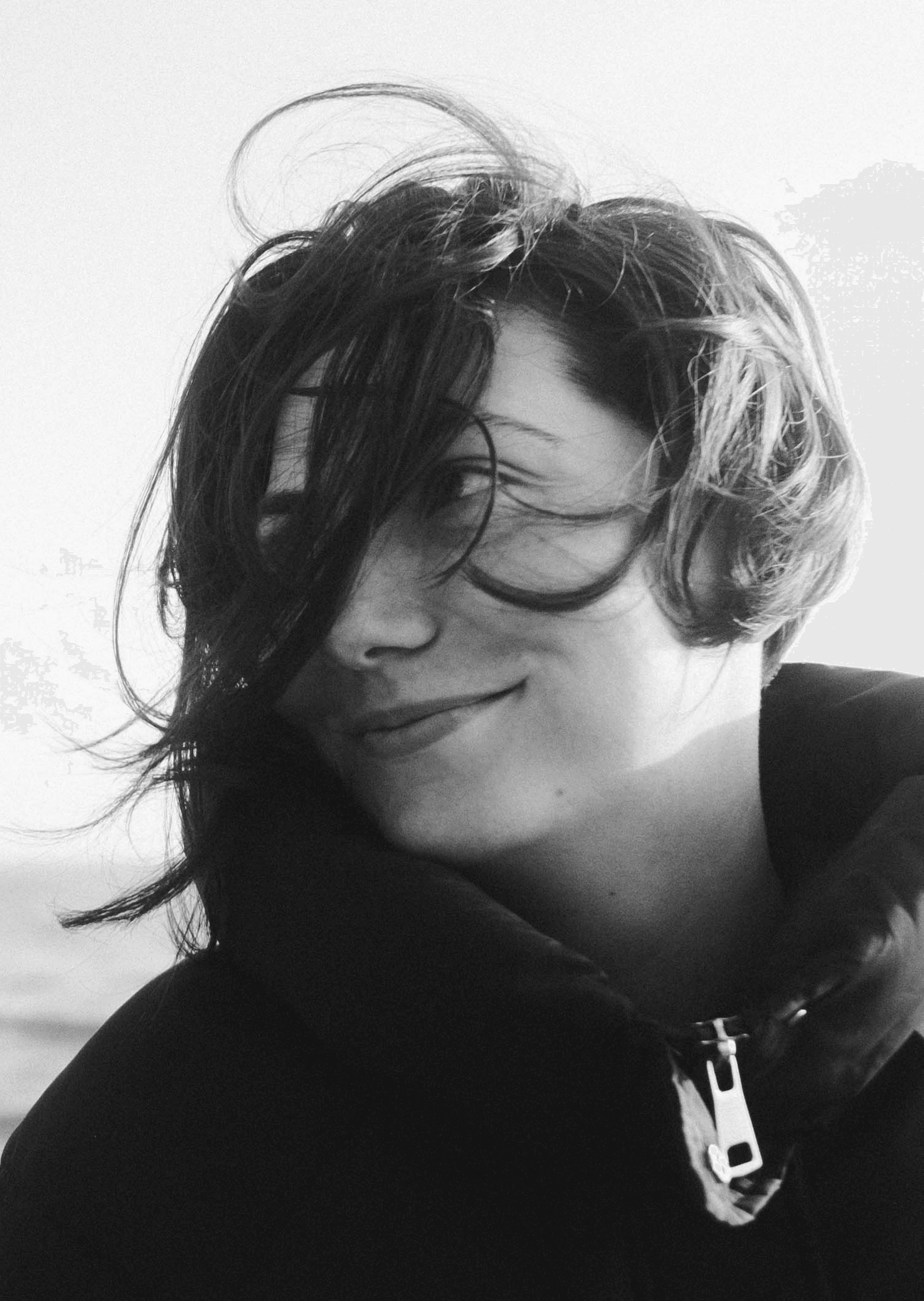 A smiling person with windblown hair.