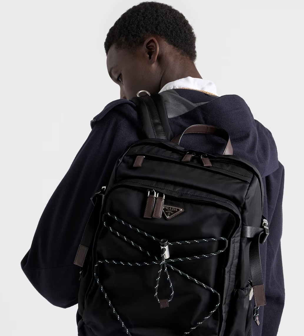 Man in a sporty jacket and light shorts walking across a football field, confidently pulling on his collar.