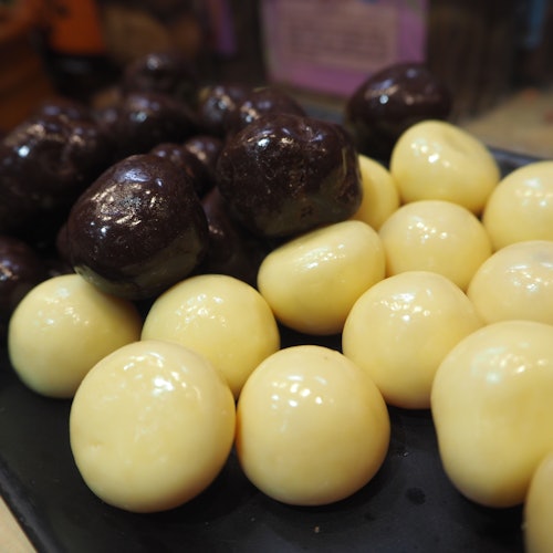 特写镜头展示一个盘子，上面排列着白巧克力和黑巧克力涂层的圆形糖果，分成两个独立的群组。