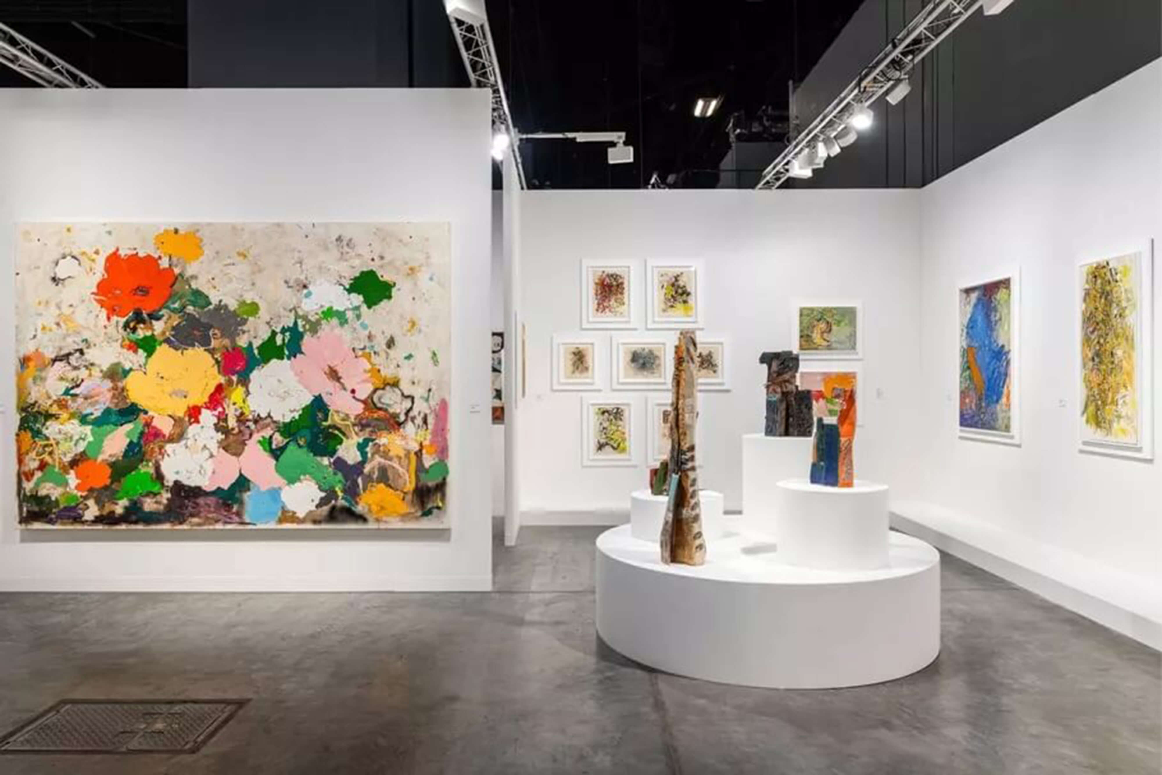 Gallery with a large abstract floral painting and tall sculptural pieces on white pedestal displays.