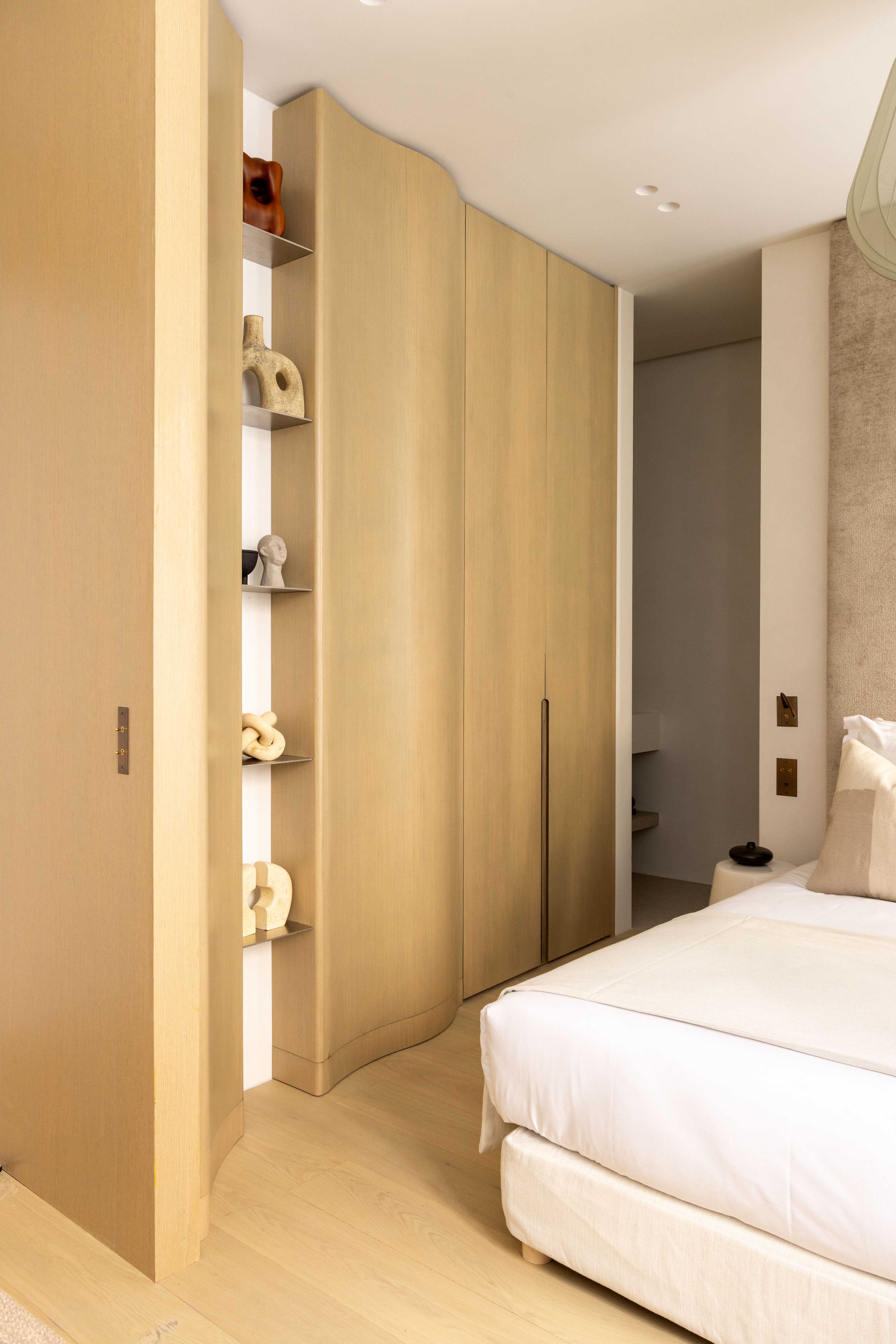 Penderie en bois clair aux formes arrondies avec niches decoratives et sculptures artisanales