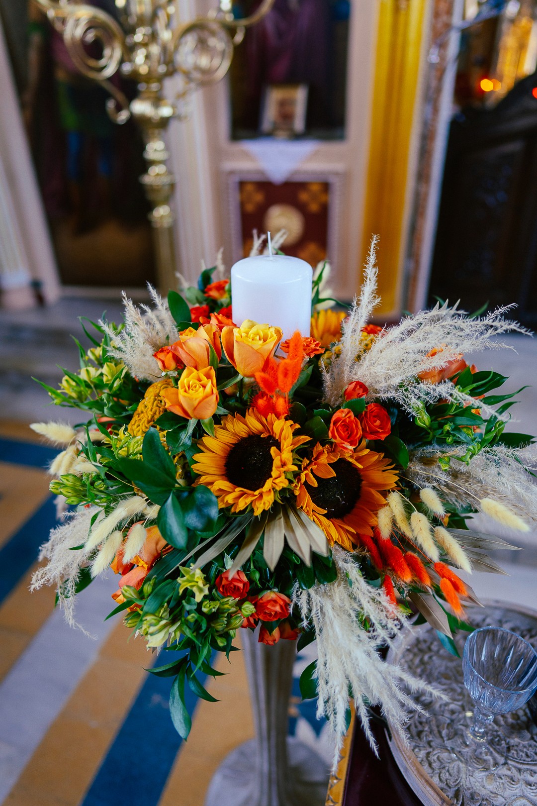 Στολισμός λαμπάδας γάμου με ηλιοτρόπια, πορτοκαλί τριαντάφυλλα και pampas grass