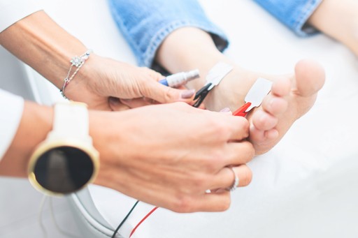 Neurologist setting electrodes on the foot of a patient prior nerve stimulation during evoked potential study