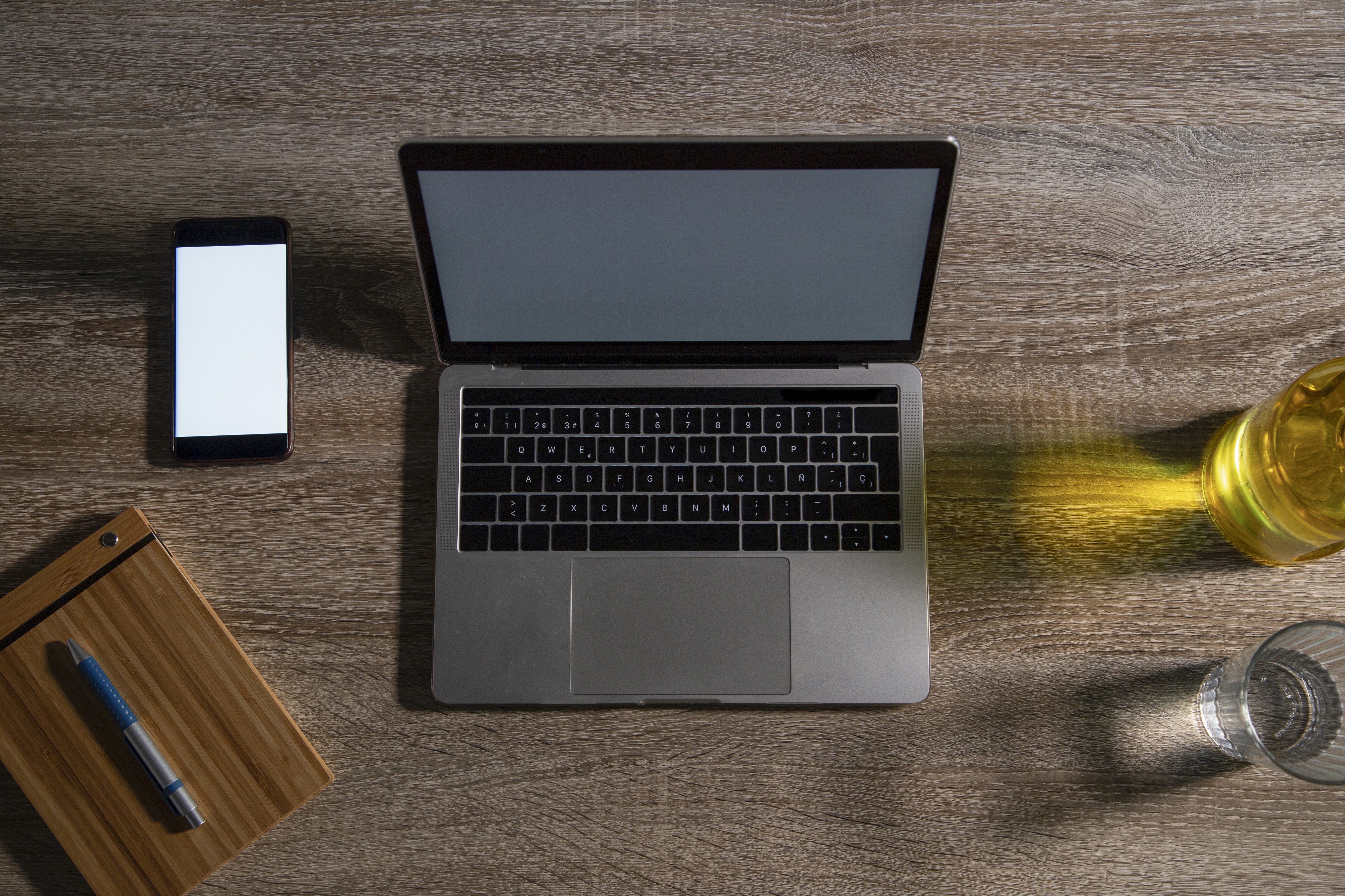 Flat lay of a laptop, smartphone, and notepad on a wooden desk representing cross-device web design.