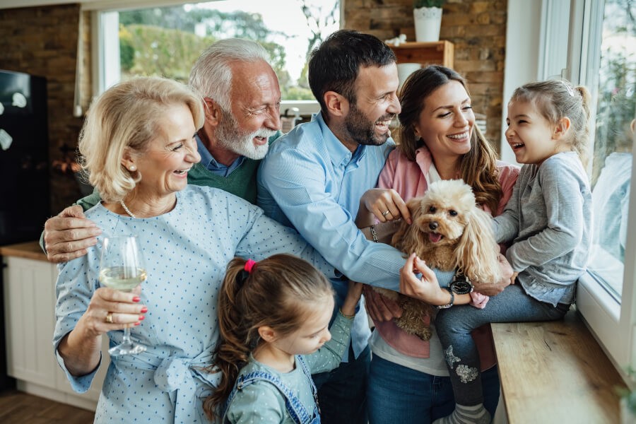 Familie fericită de trei generații zâmbind acasă, simțindu-se în siguranță datorită asigurărilor BIXMA.