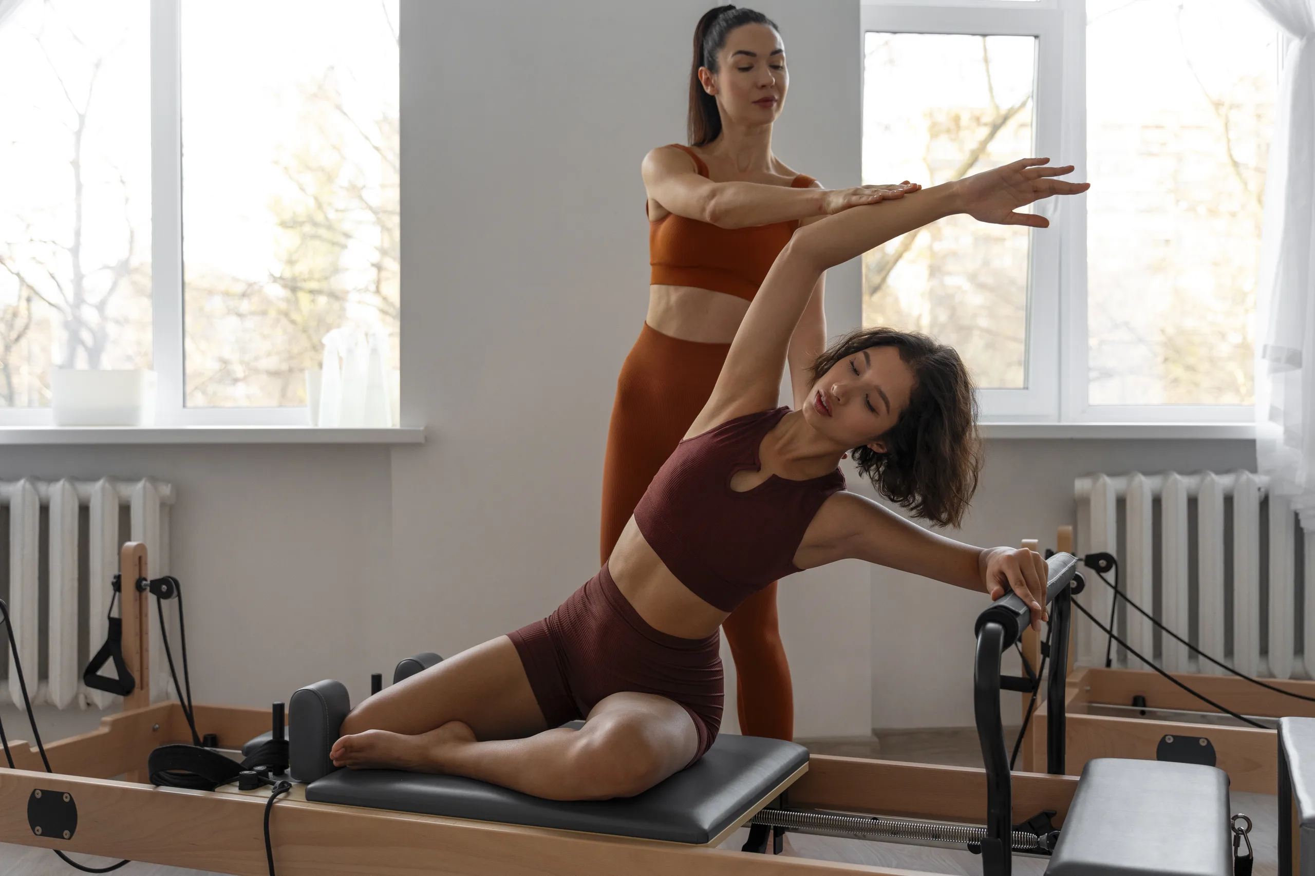 mulher praticando pilates em aparelho reformer com alongamento