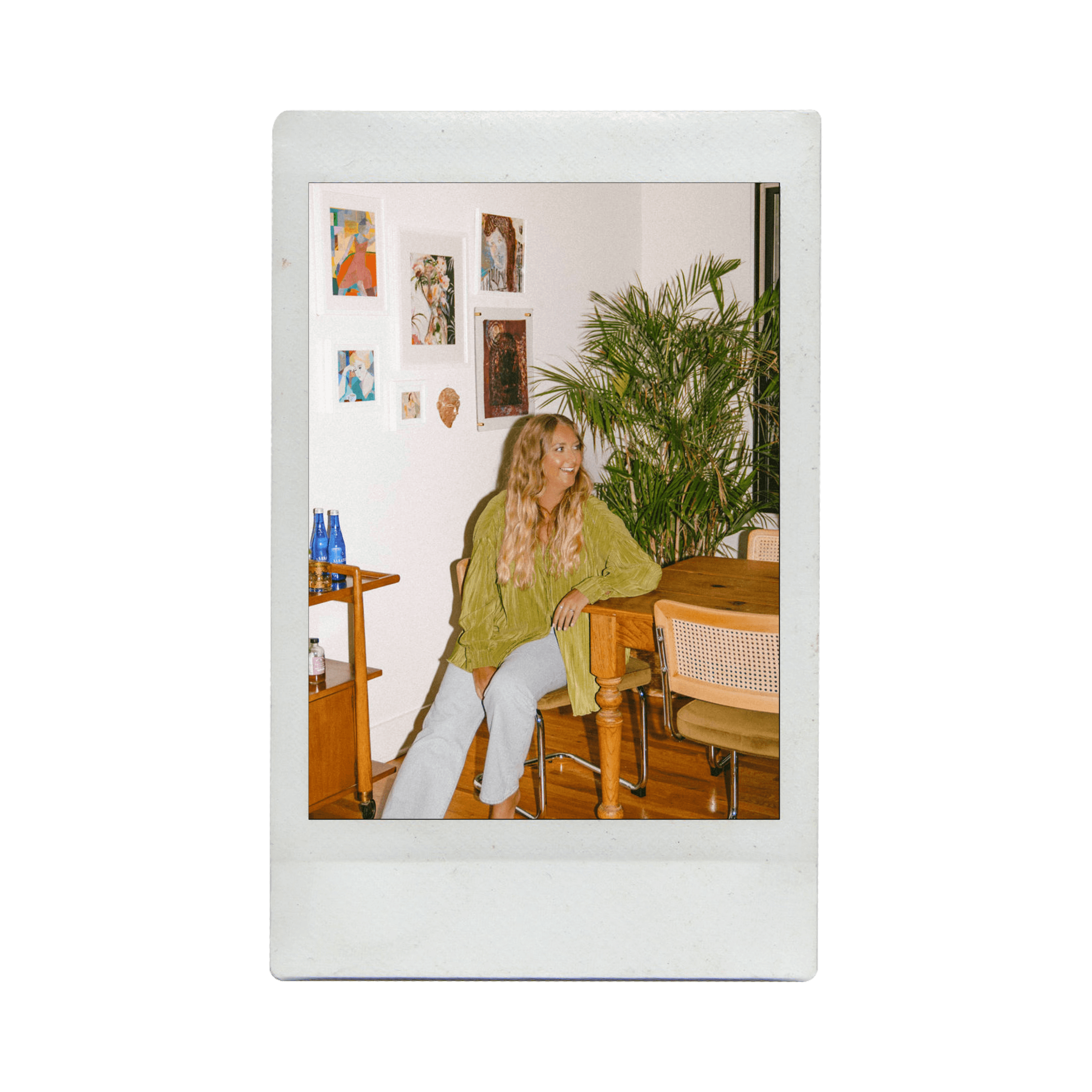 Close-up of a person with light hair, blue eyes, and bold red lips framed by a dark hood.