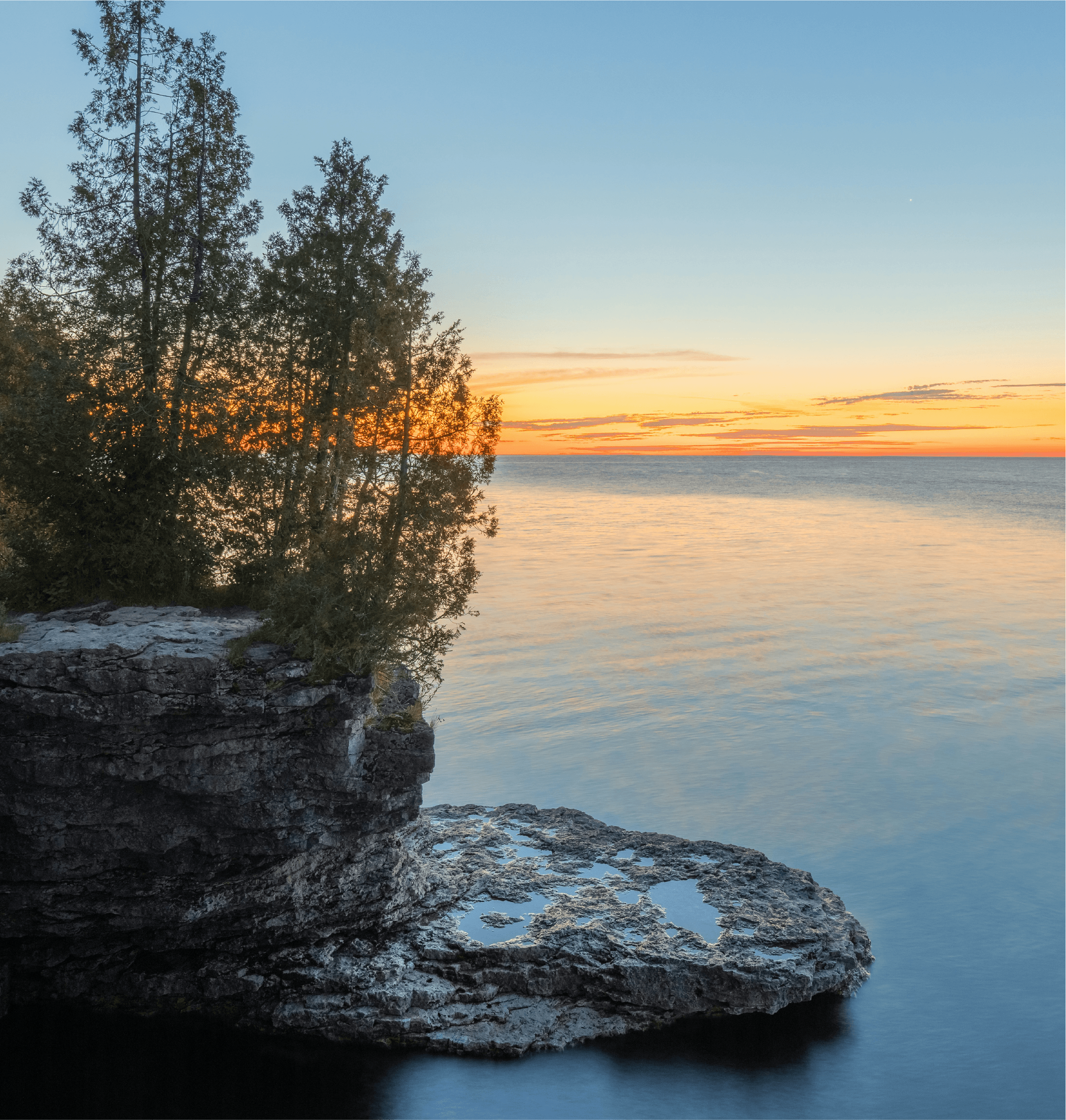Rocky coastal shoreline with trees at sunset along Royal River watershed