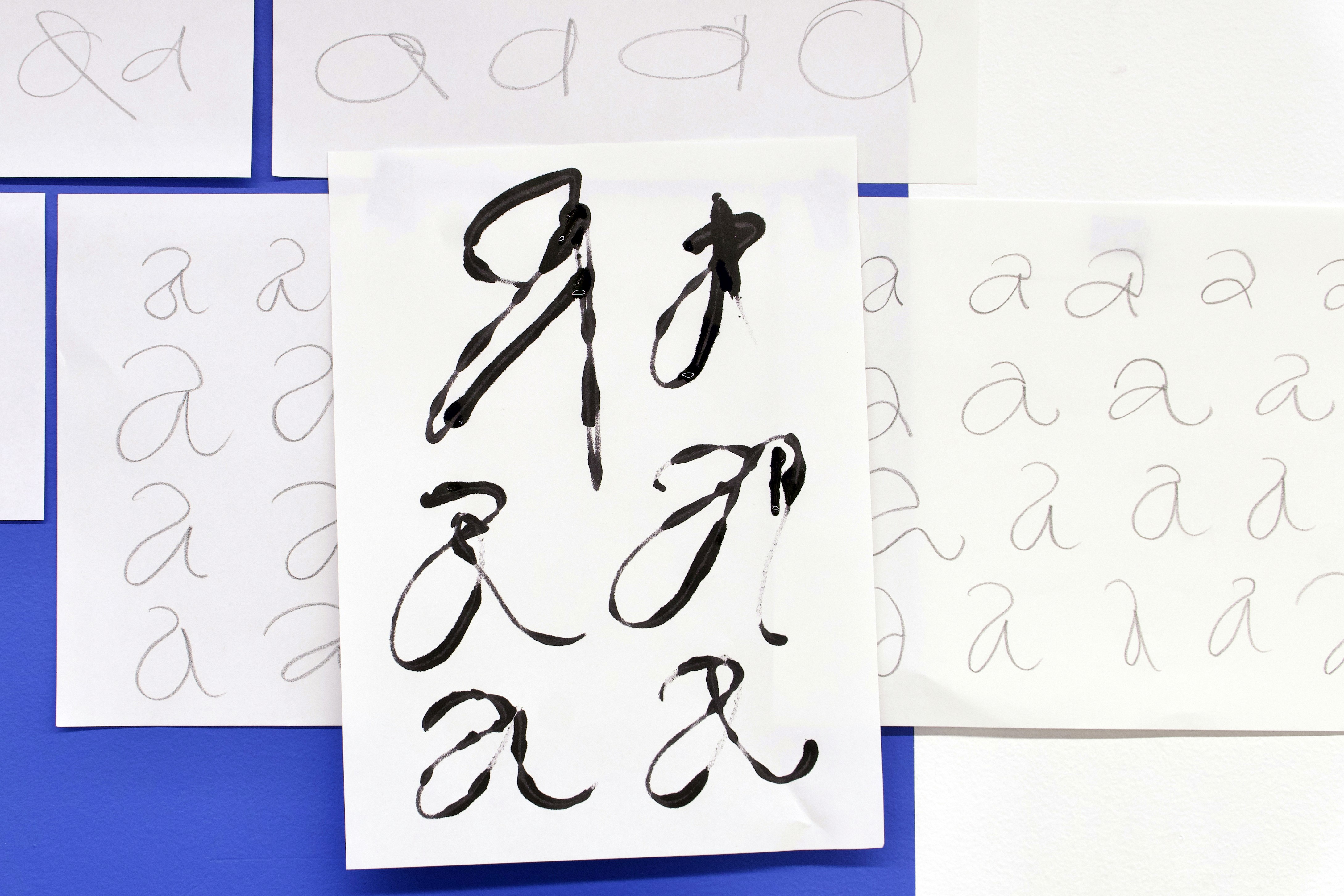 Expressive hand-drawn letters on paper on blue wall