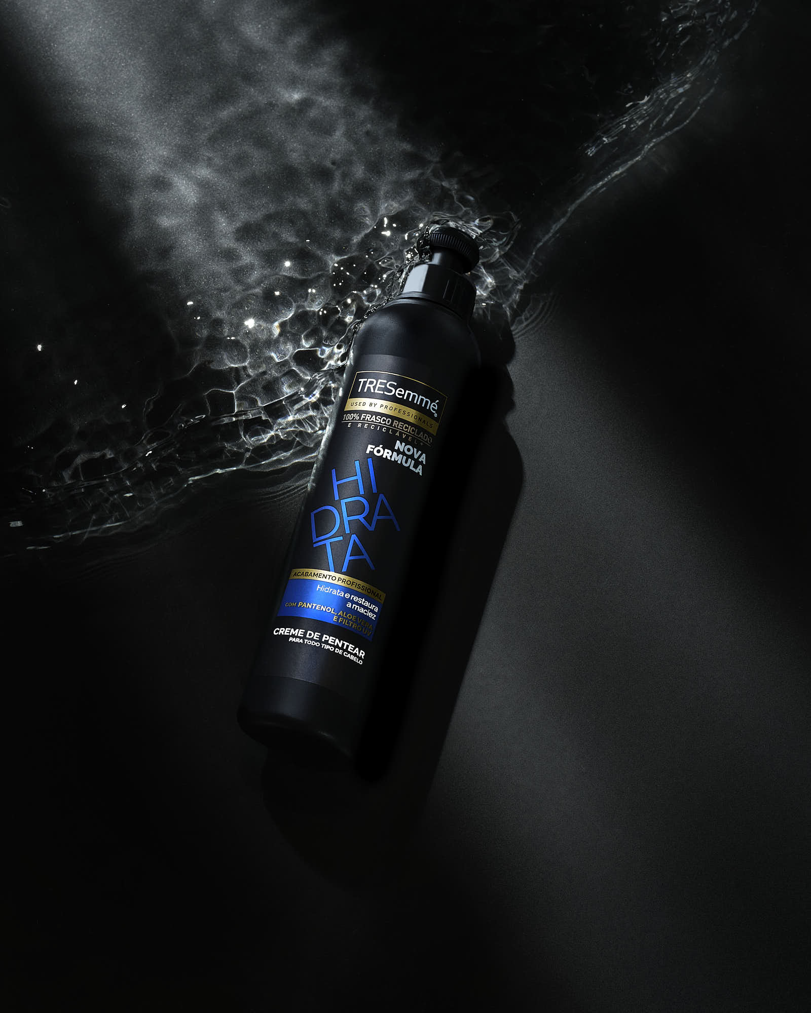 A black bottle with a blue label, illuminated against a dark, textured background with soft light effects.