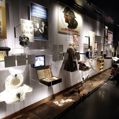Museiutställning med föremål från andra världskriget, inklusive affischer, uniformer, gasmasker och informationsdisplayer.