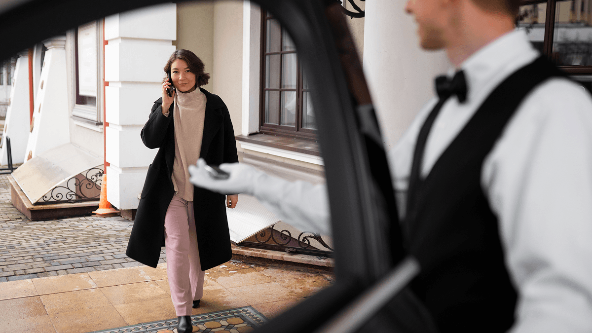 Concierge en tenue formelle accueillant une cliente élégante à l'entrée d'un établissement de luxe
