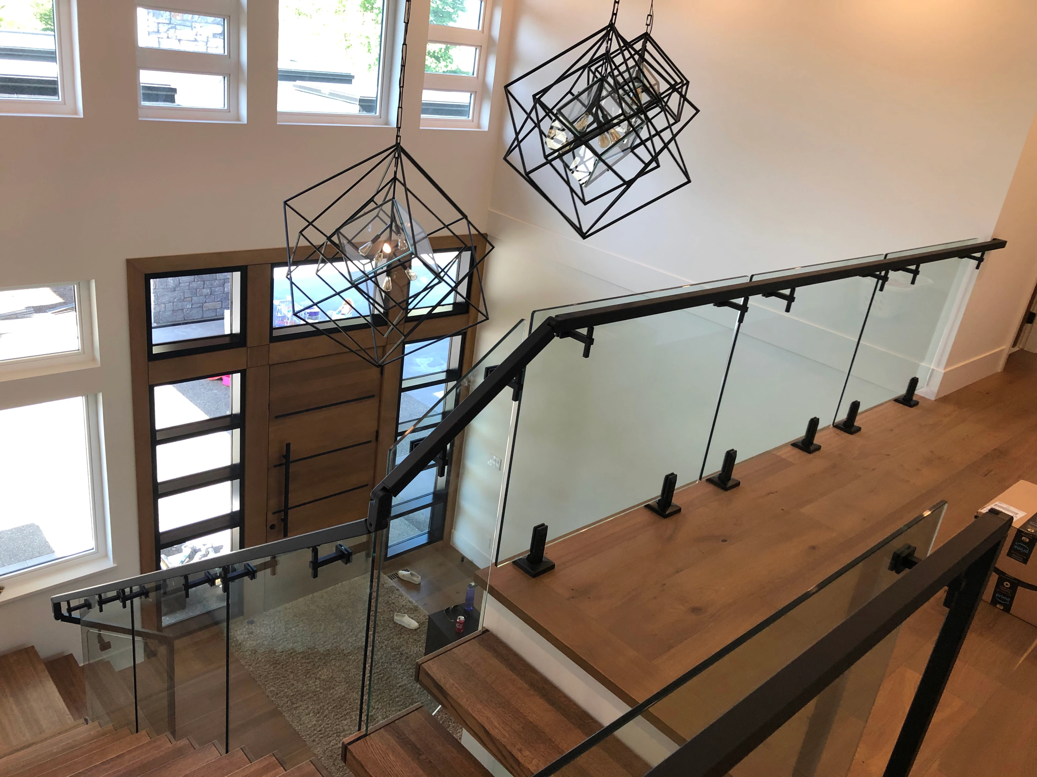 A dramatic curved interior staircase featuring warm under-tread LED lighting and a curved standoff glass railing with a silver handrail.