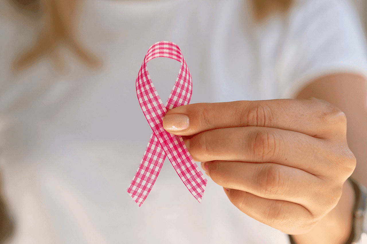 Persona sosteniendo lazo rosa, símbolo de la concientización sobre el cáncer de mamá.