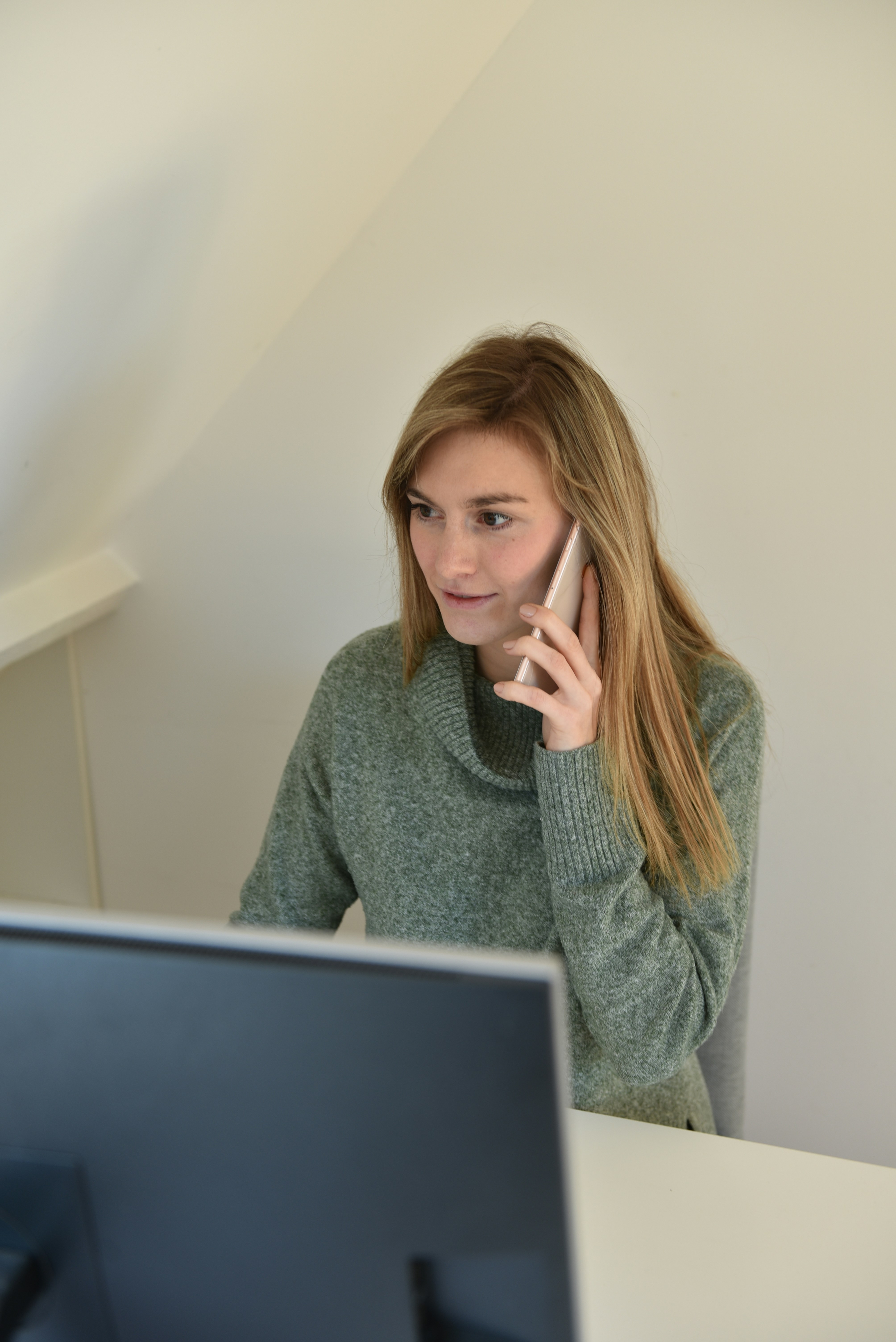a woman sitting in front of a computer talking on a cell phone